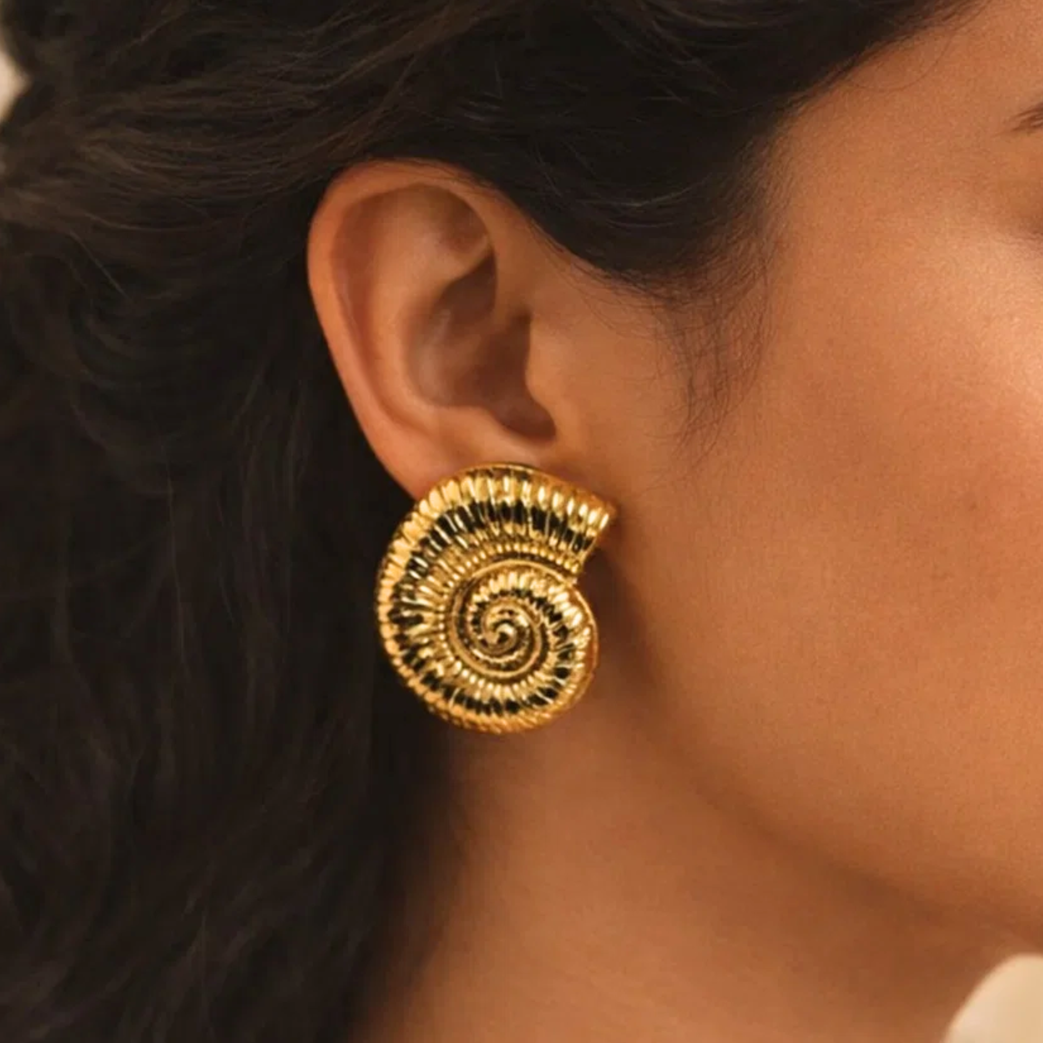 Close-up of a person wearing a gold spiral earring.