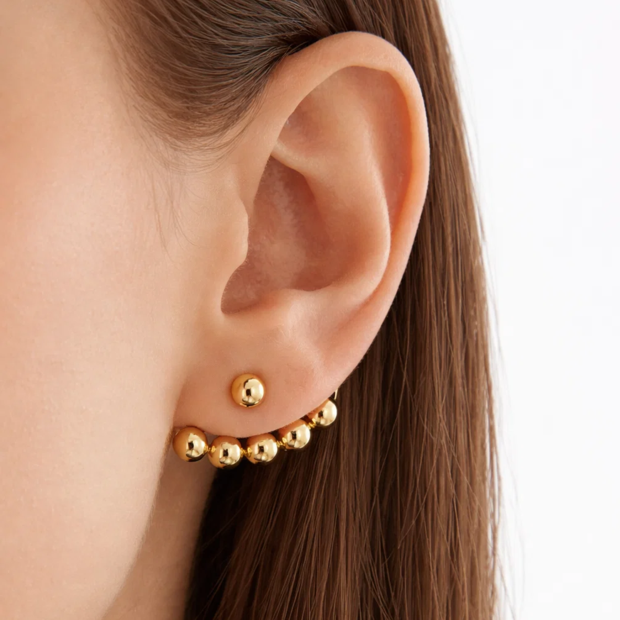 A woman wearing a beaded gold earring