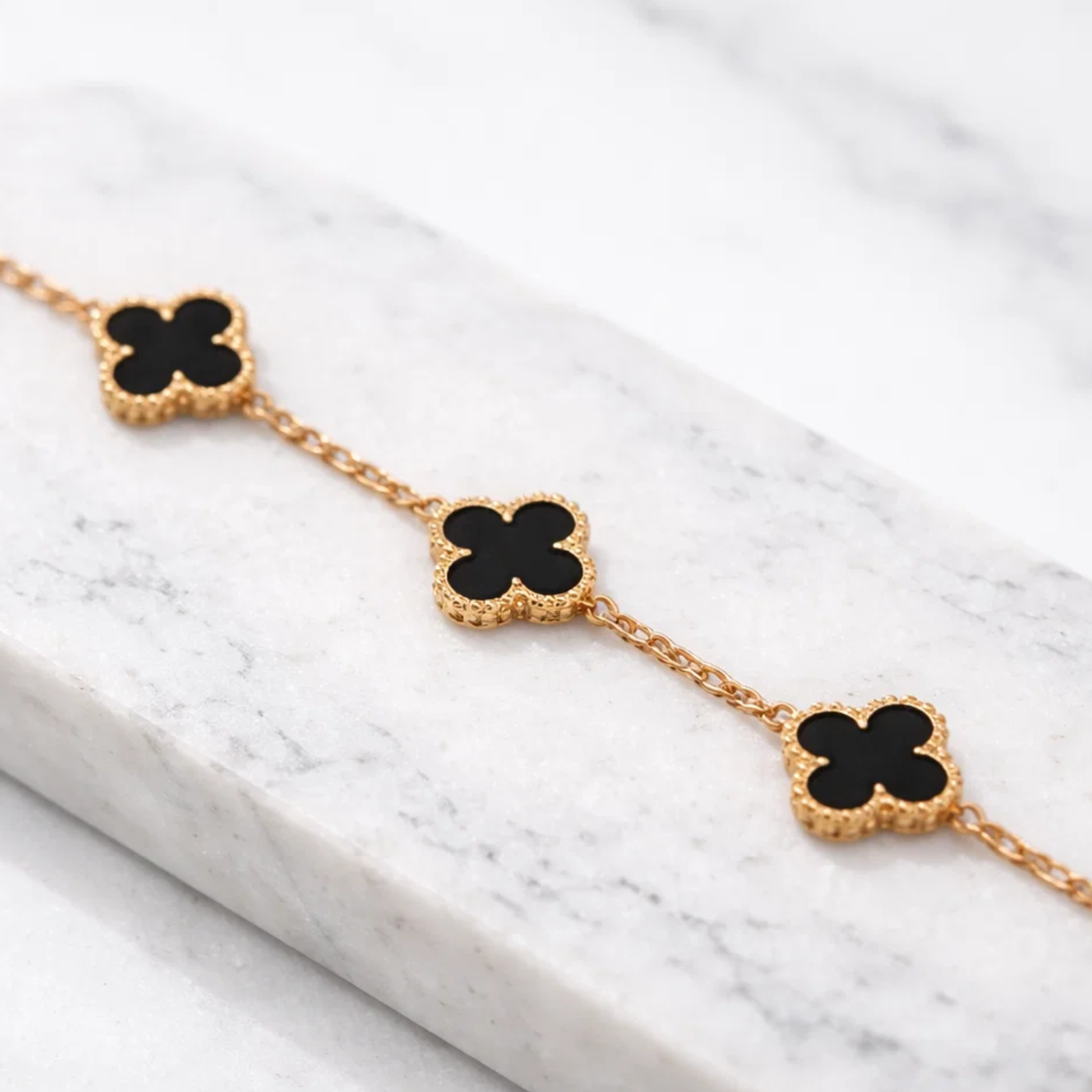 Black clover bracelets on a white marble 