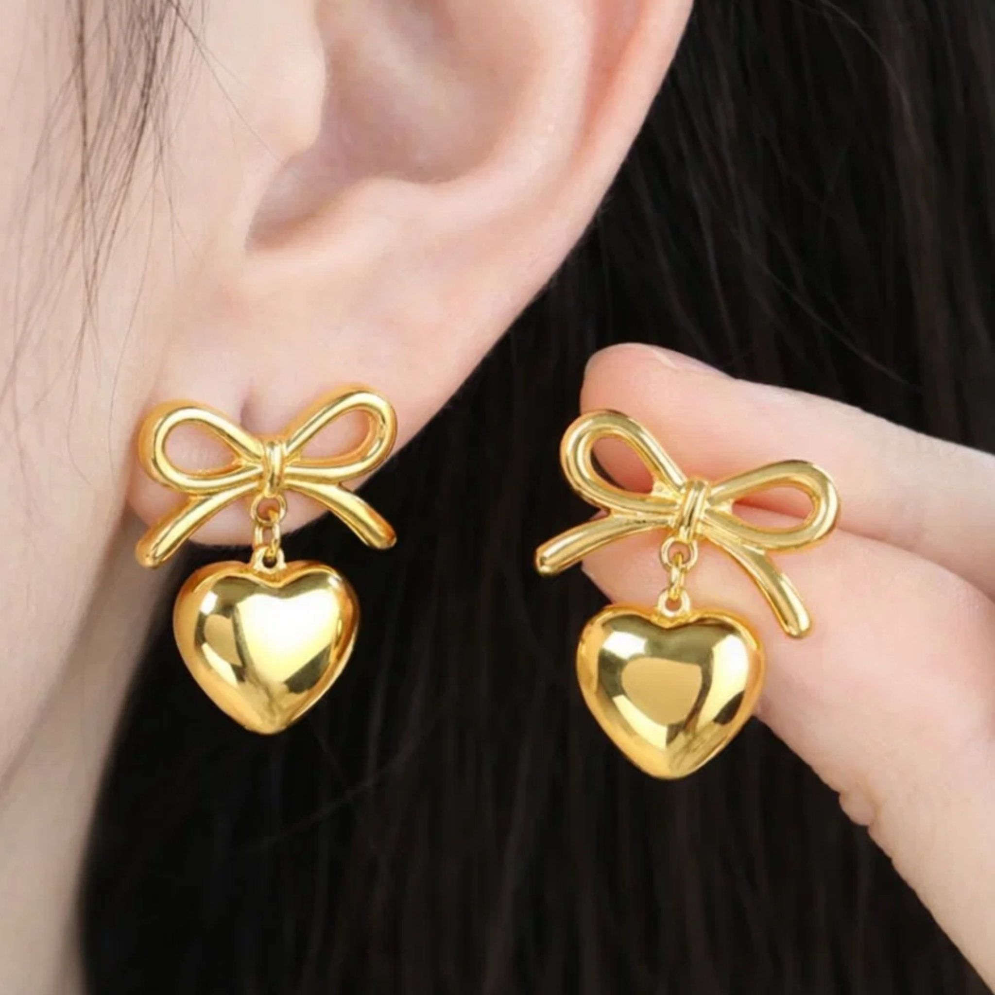 A woman wearing bow heart earrings