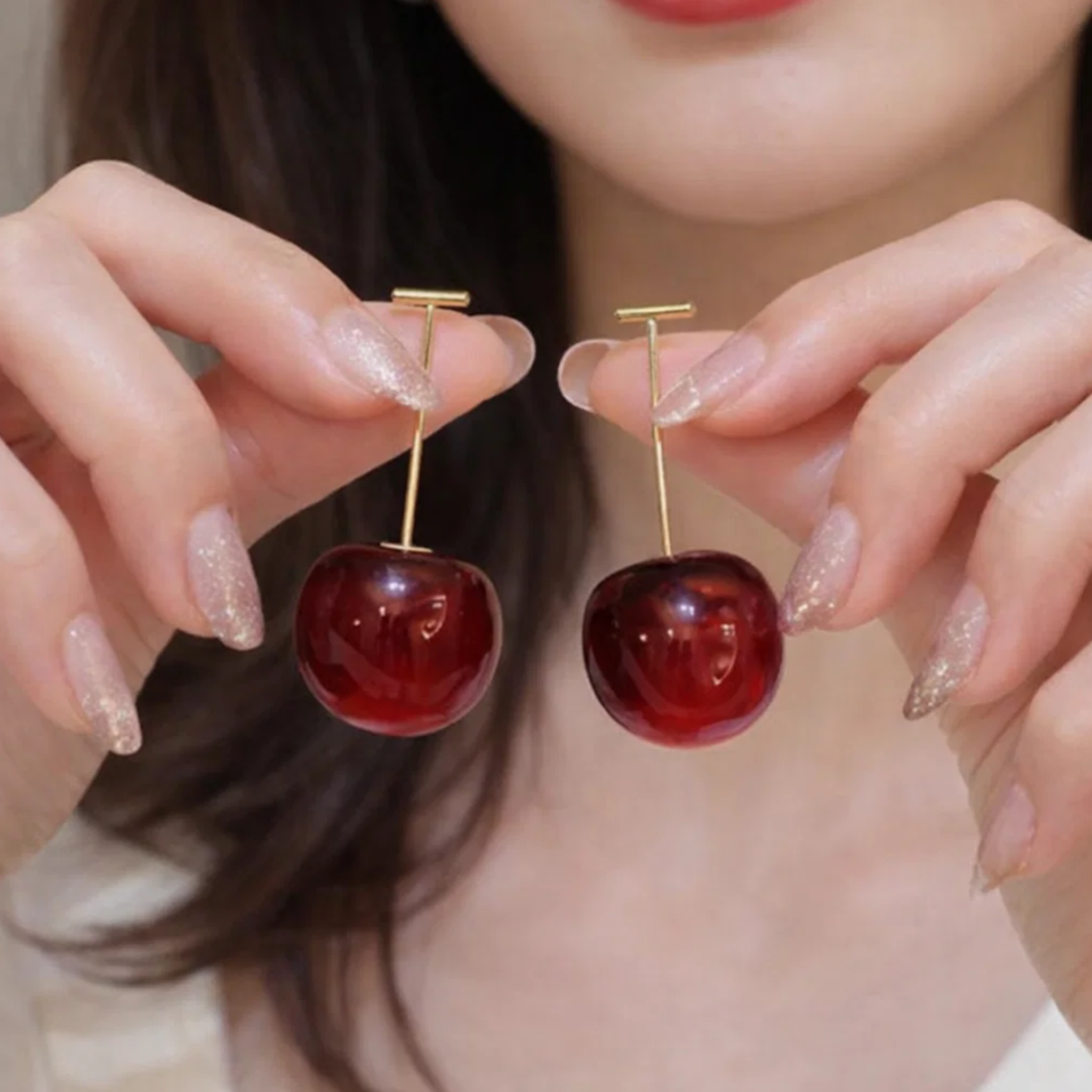 A woman holding two cherry-shaped earrings