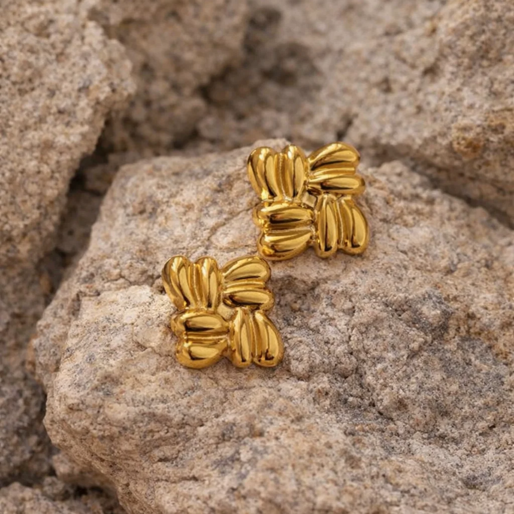 Gold cluster earrings on a rock background