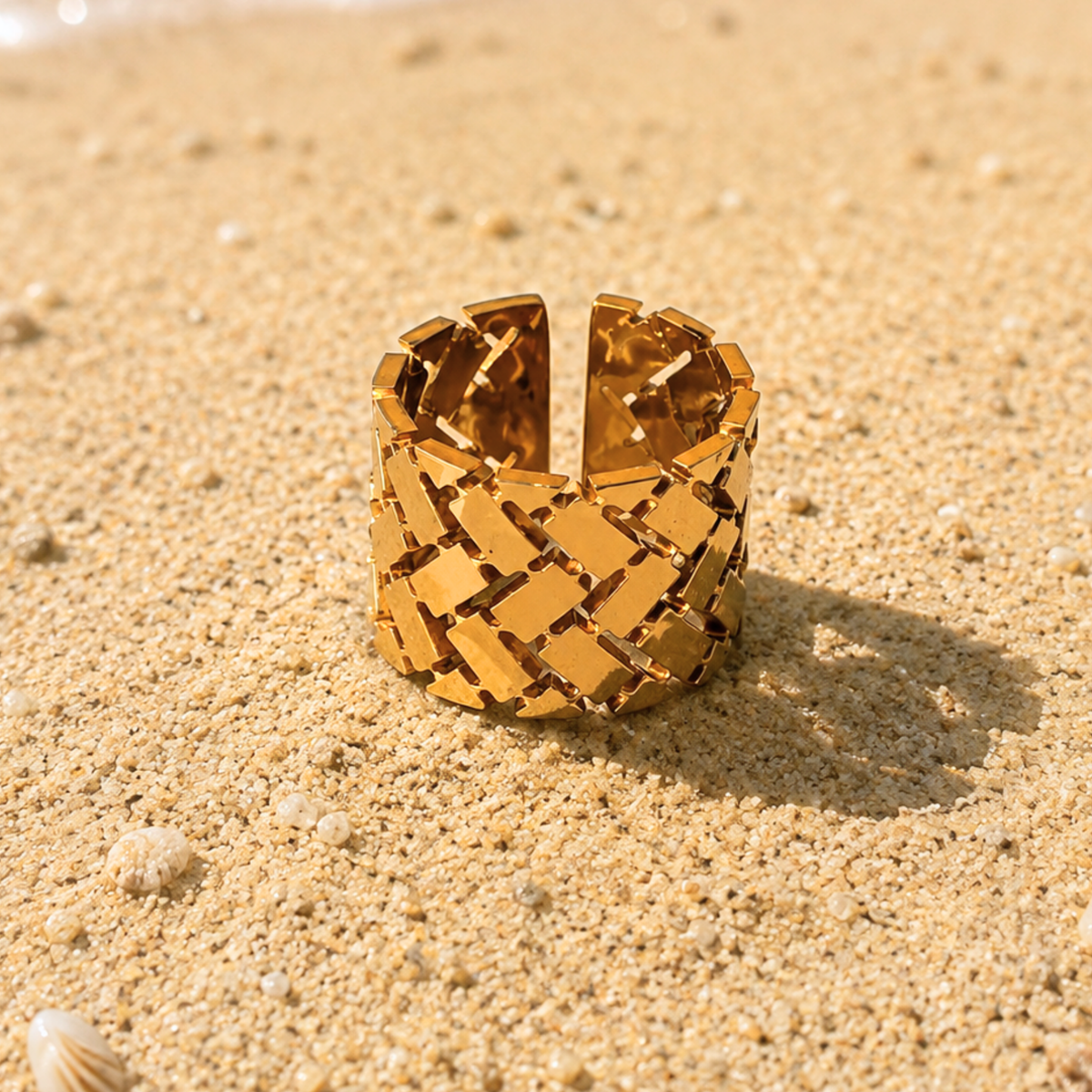 A wide, chunky gold ring with a geometric, woven-link design