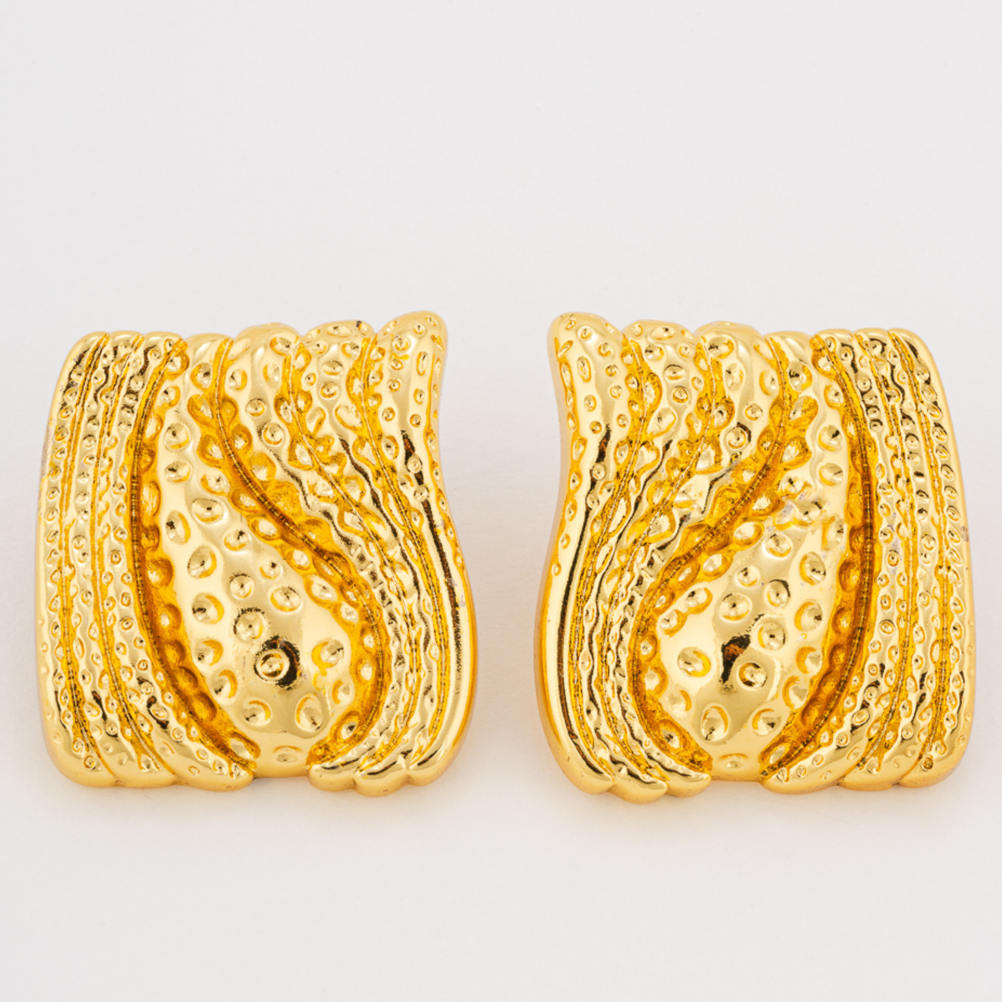 Pair of gold earrings with textured design on a white background