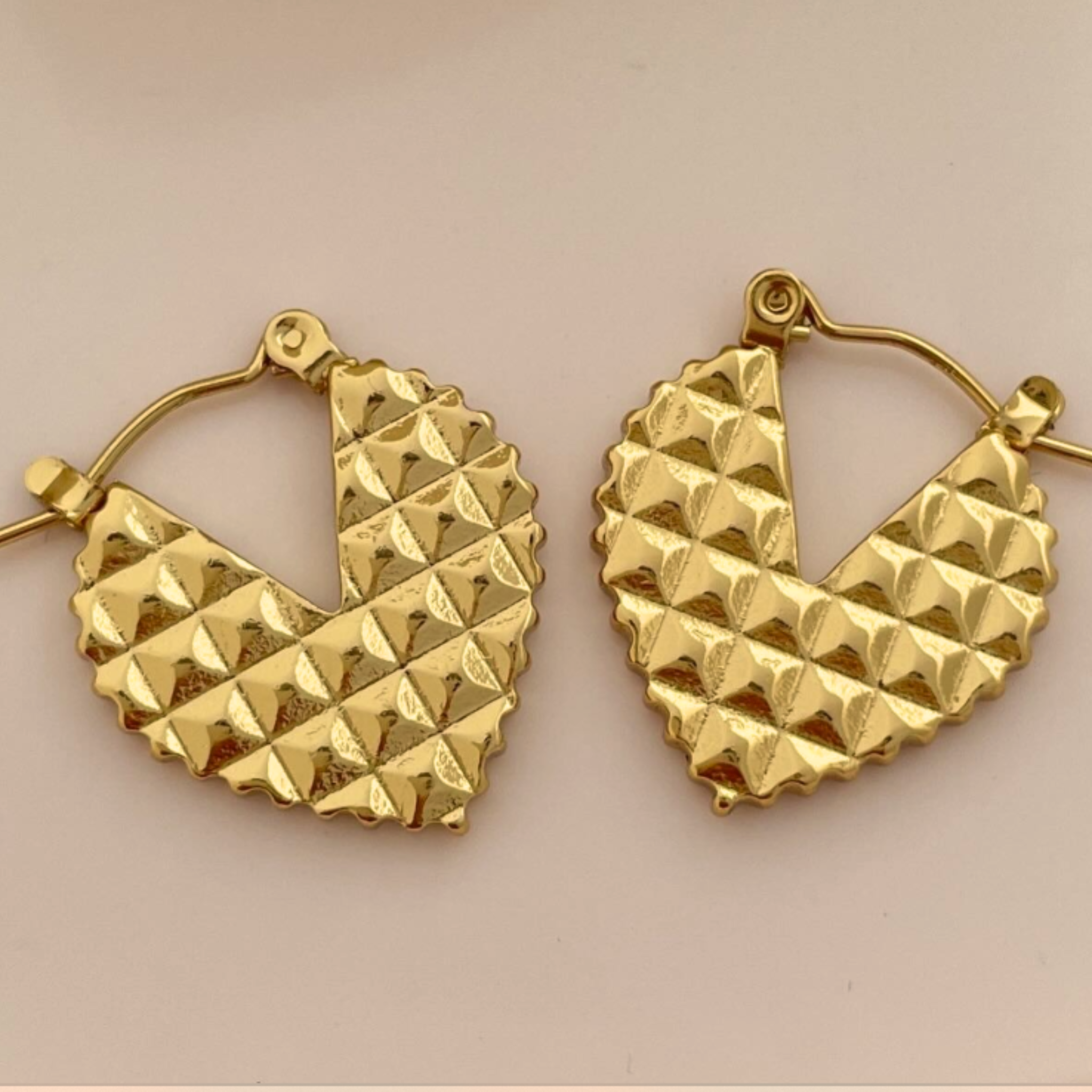 Gold hoop earrings with pyramid texture 