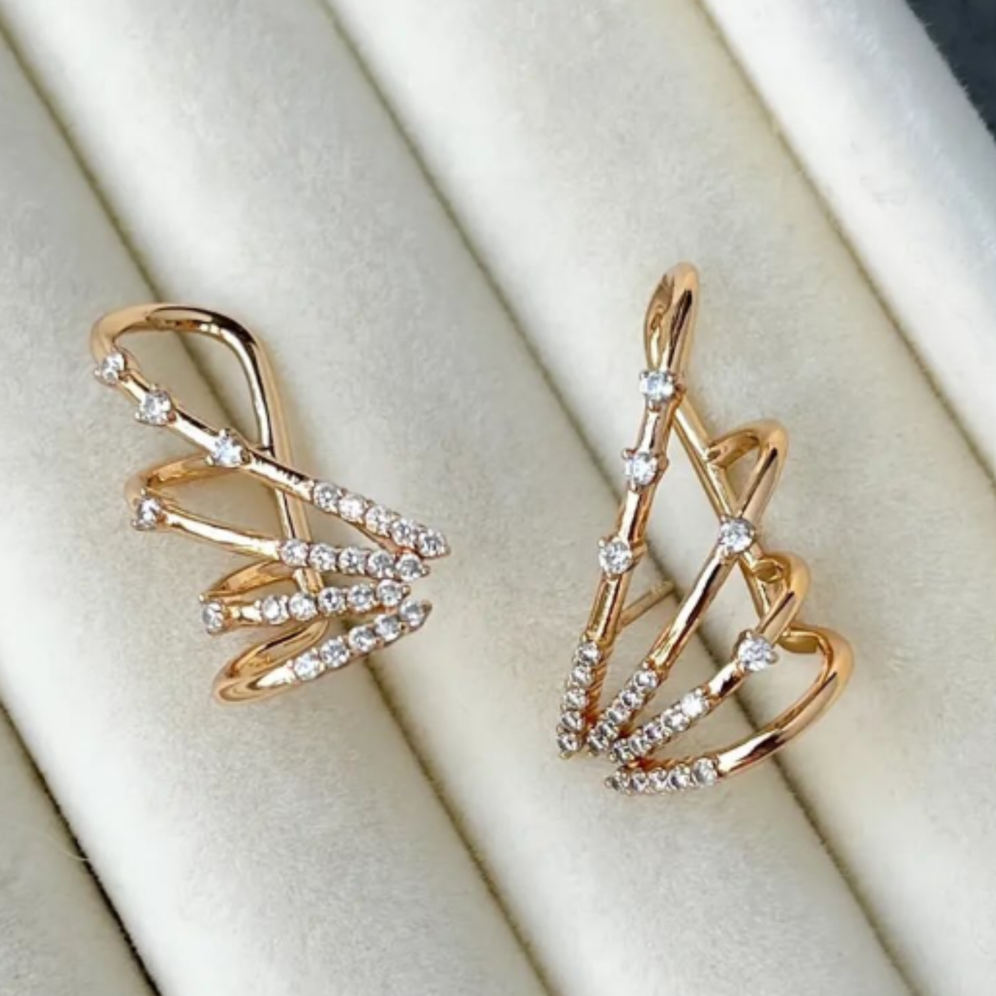 Gold wing earrings laid on a jewelry storage cushion