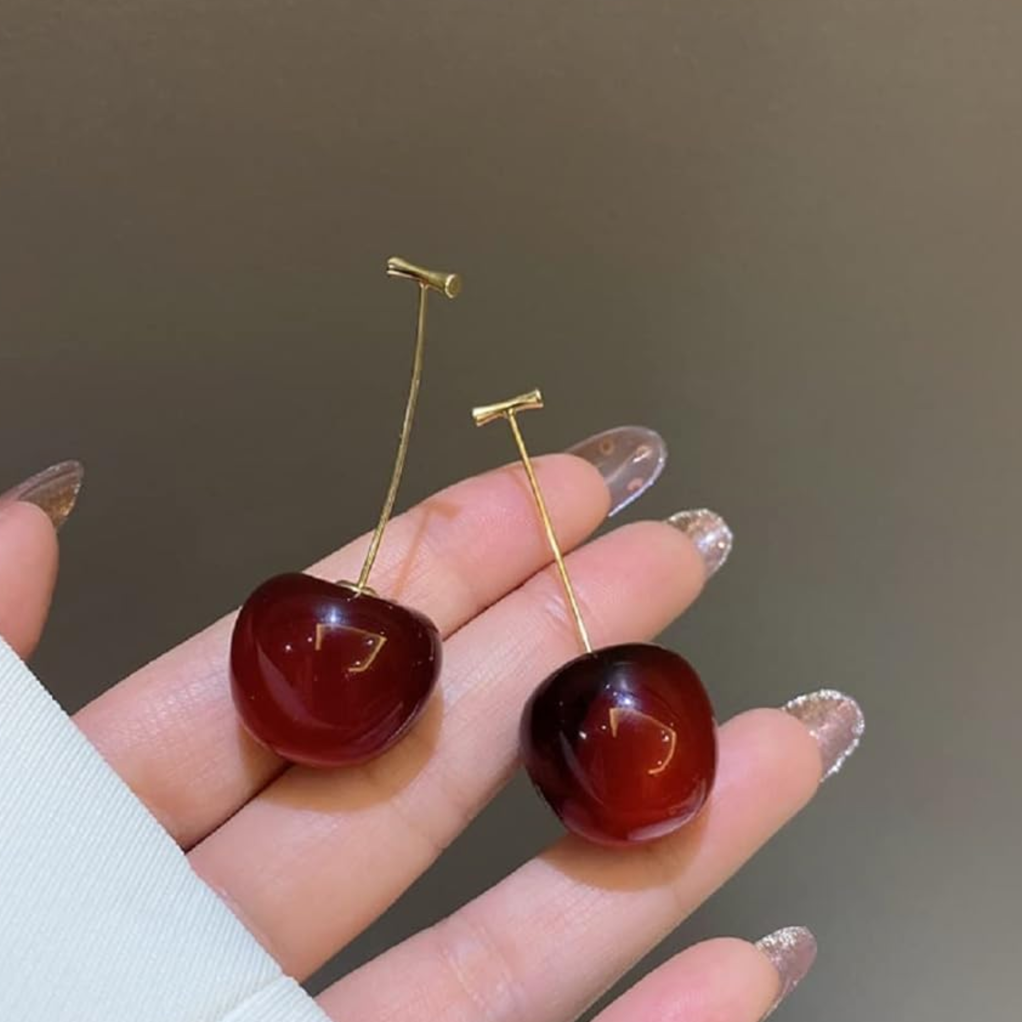 A woman holding cherry earrings