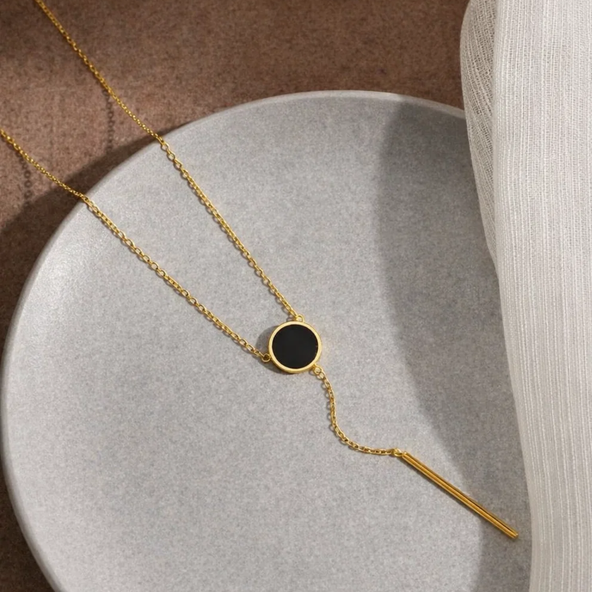 Gold necklace with a black pendant on a plate