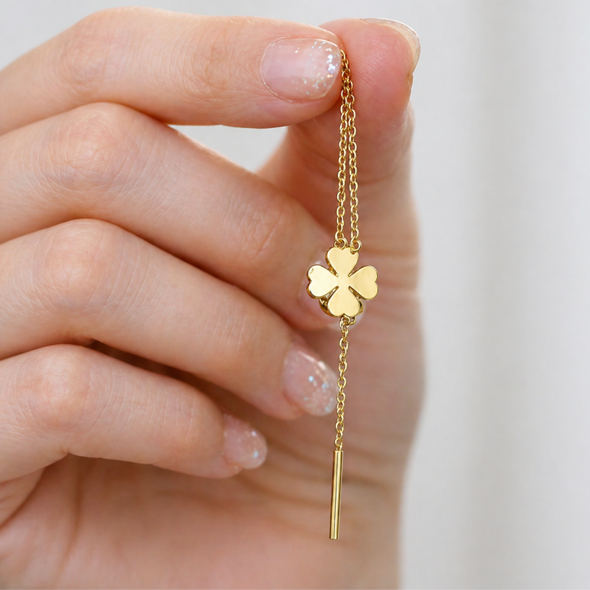 A woman holding a dangling clover earring