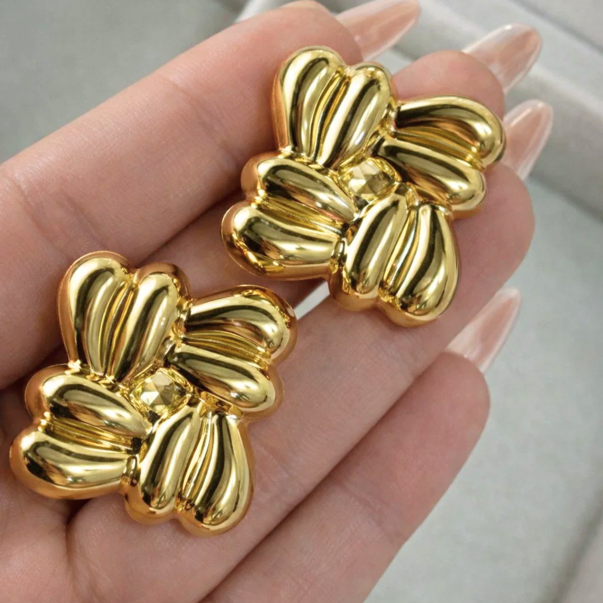 A woman holding gold cluster earrings