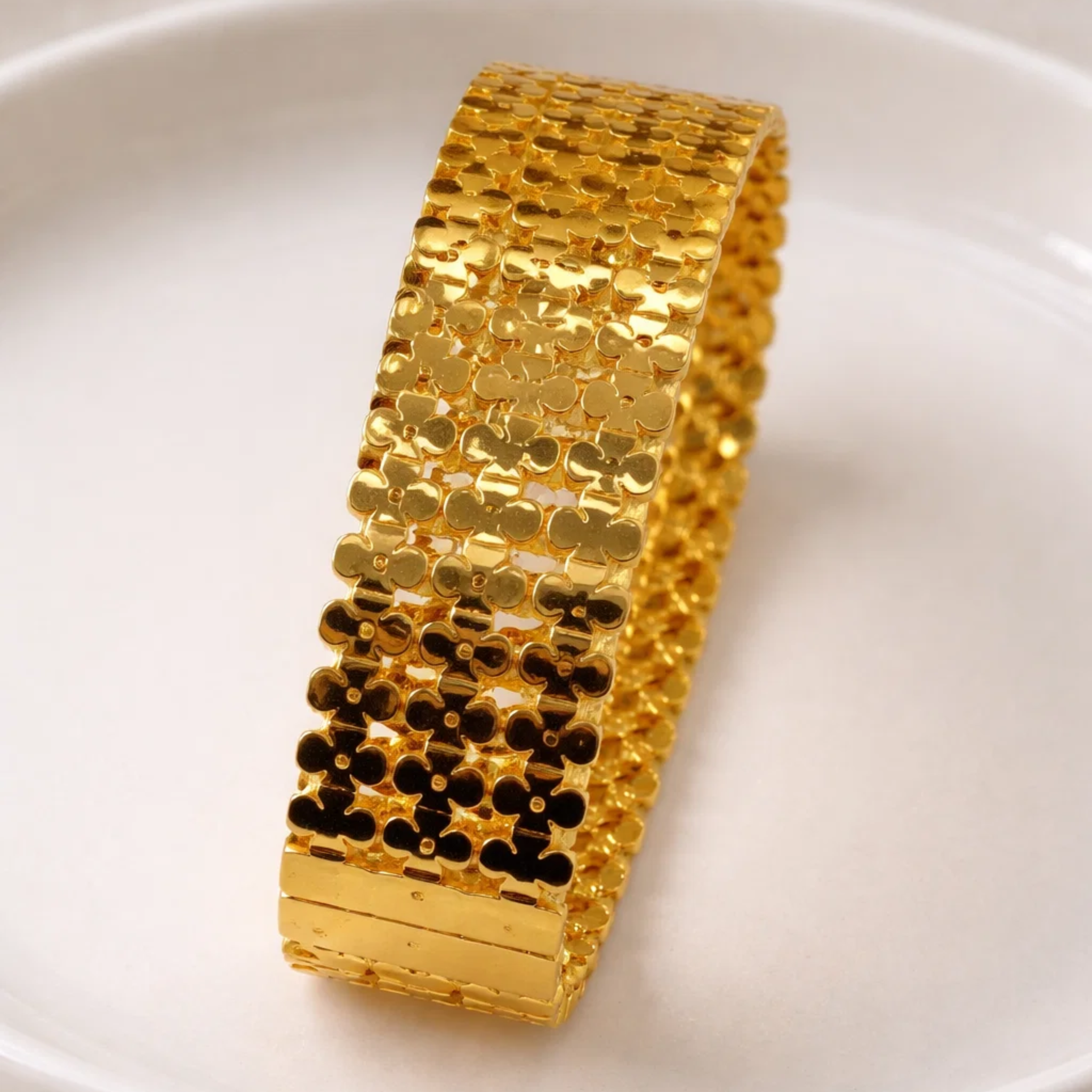 Gold cuff bangle on a ceramic plate
