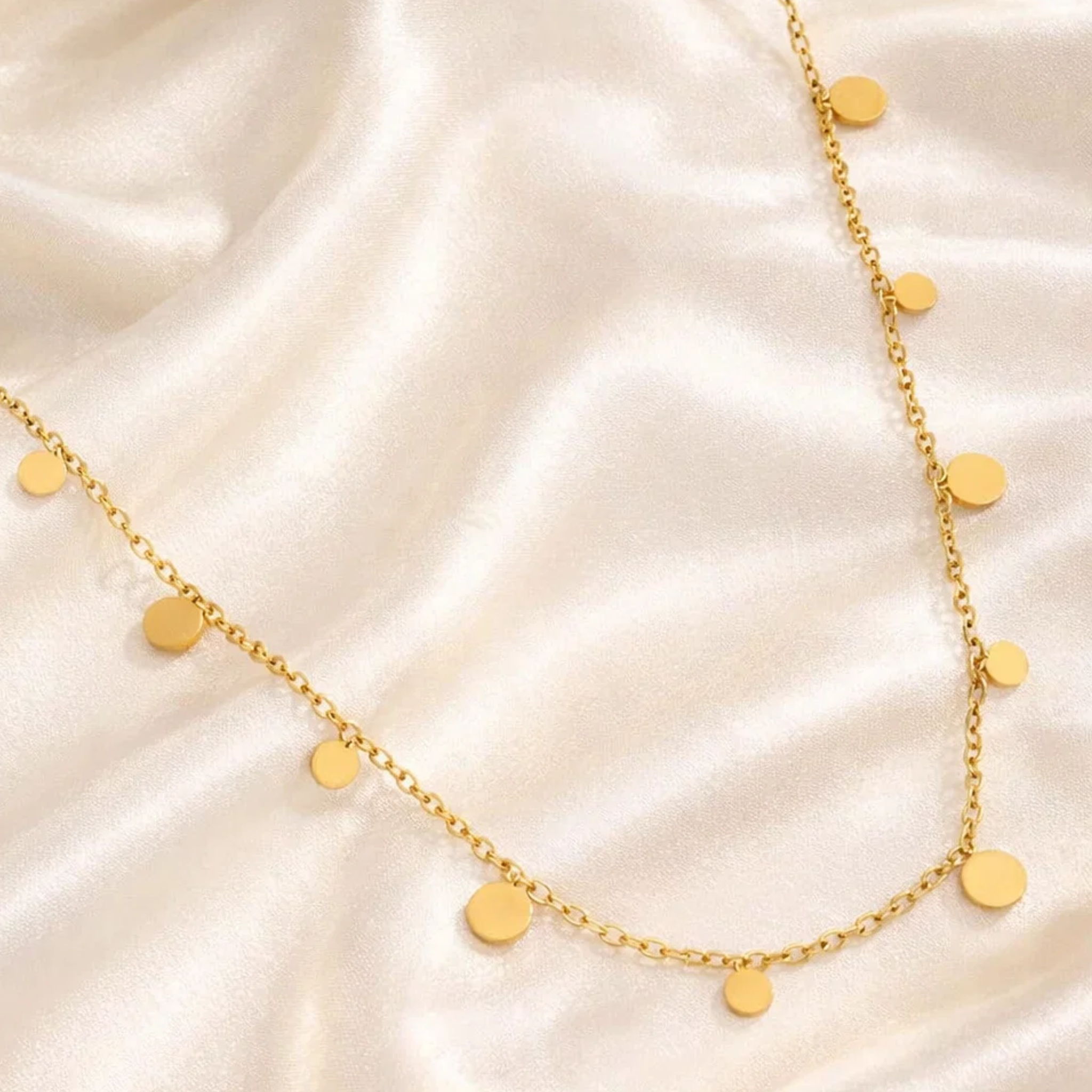 Gold necklace with round pendants on a satin surface