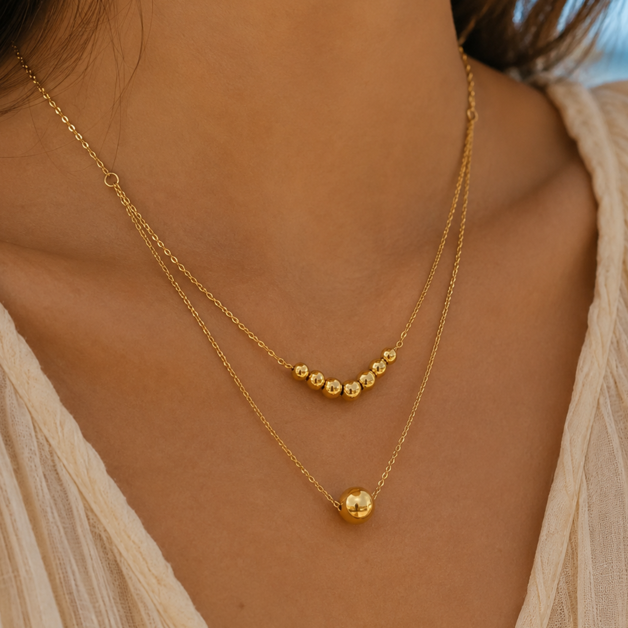 A woman wearing a double layer gold sphere necklace