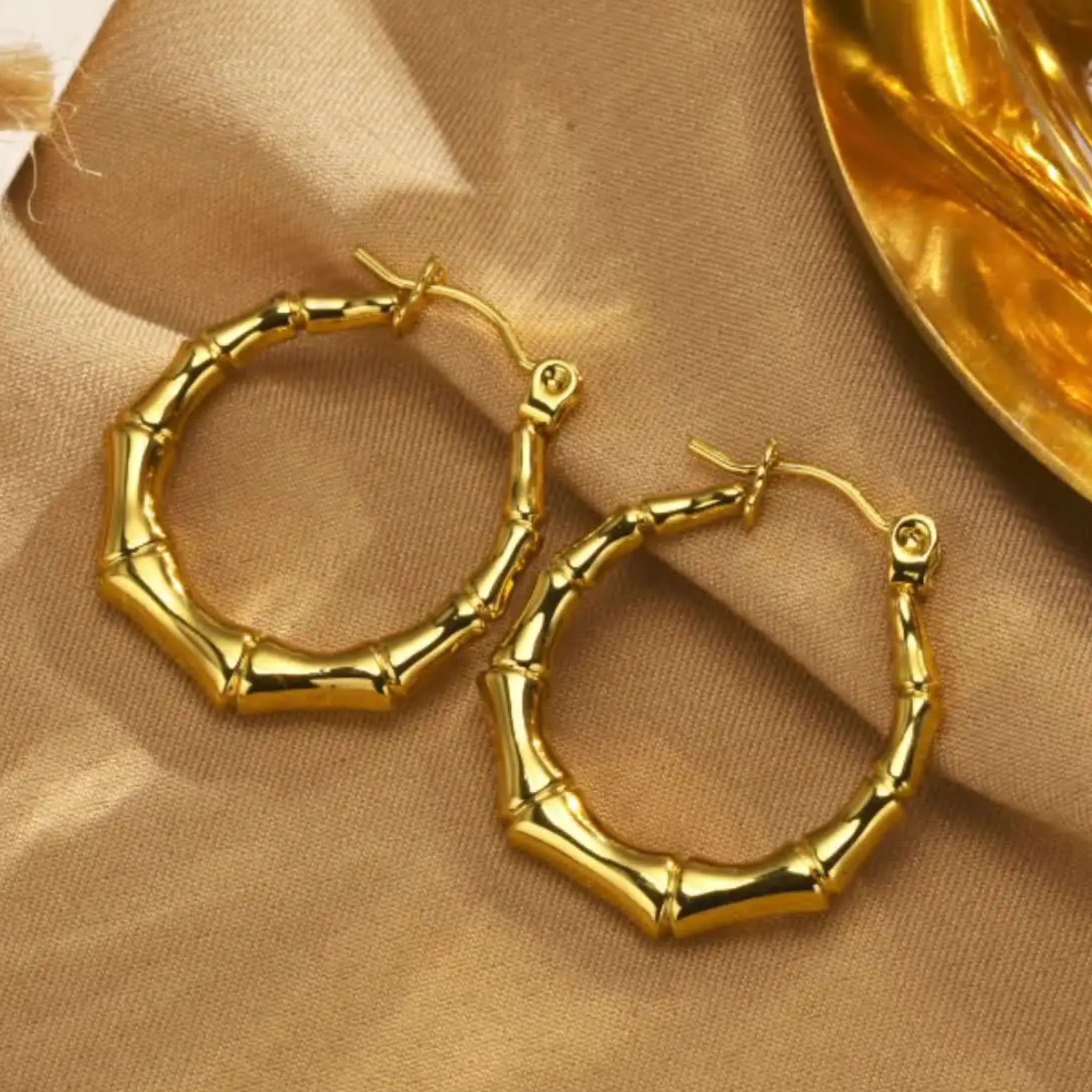 Gold hoop earrings on a beige fabric background