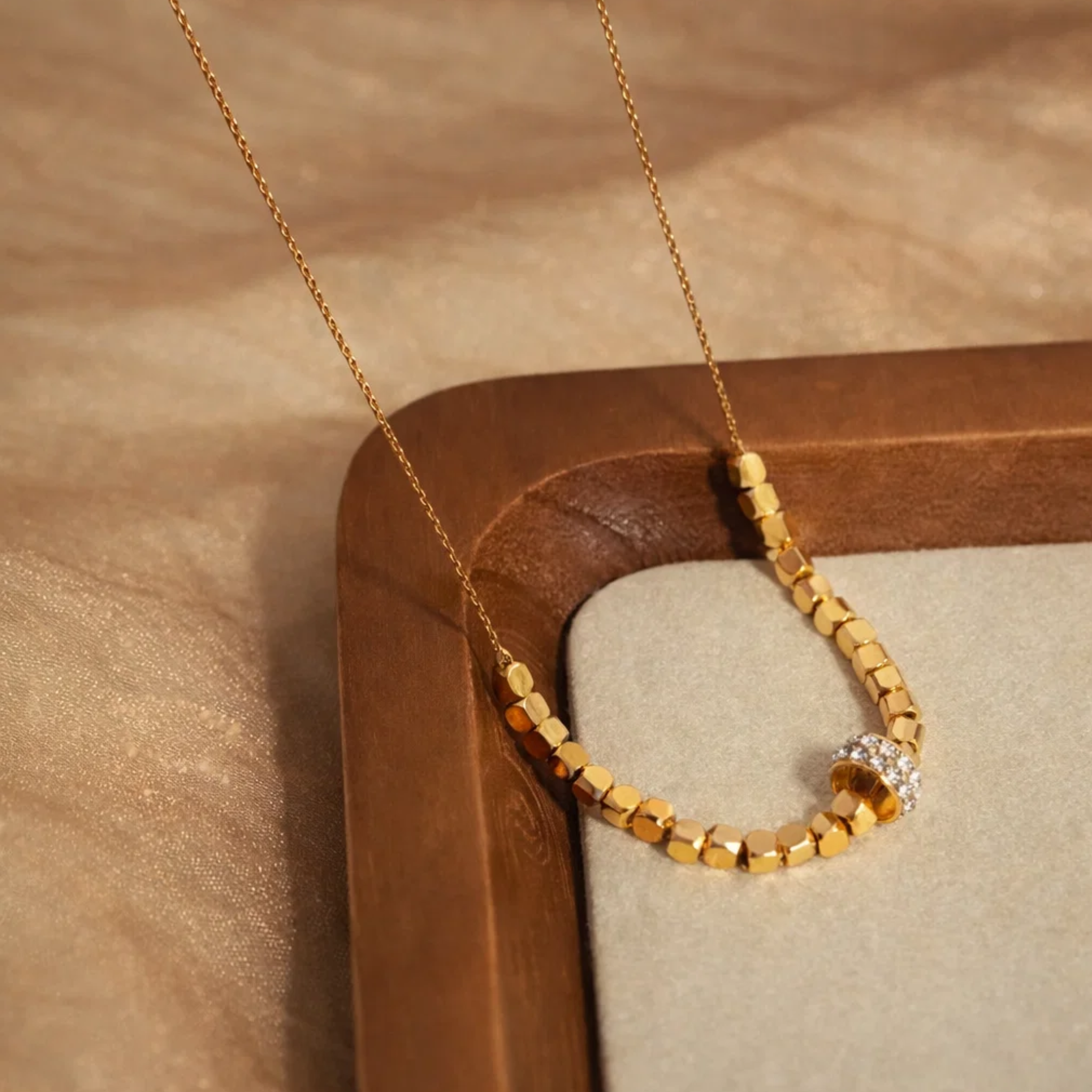 Gold beaded necklace on a wooden stand