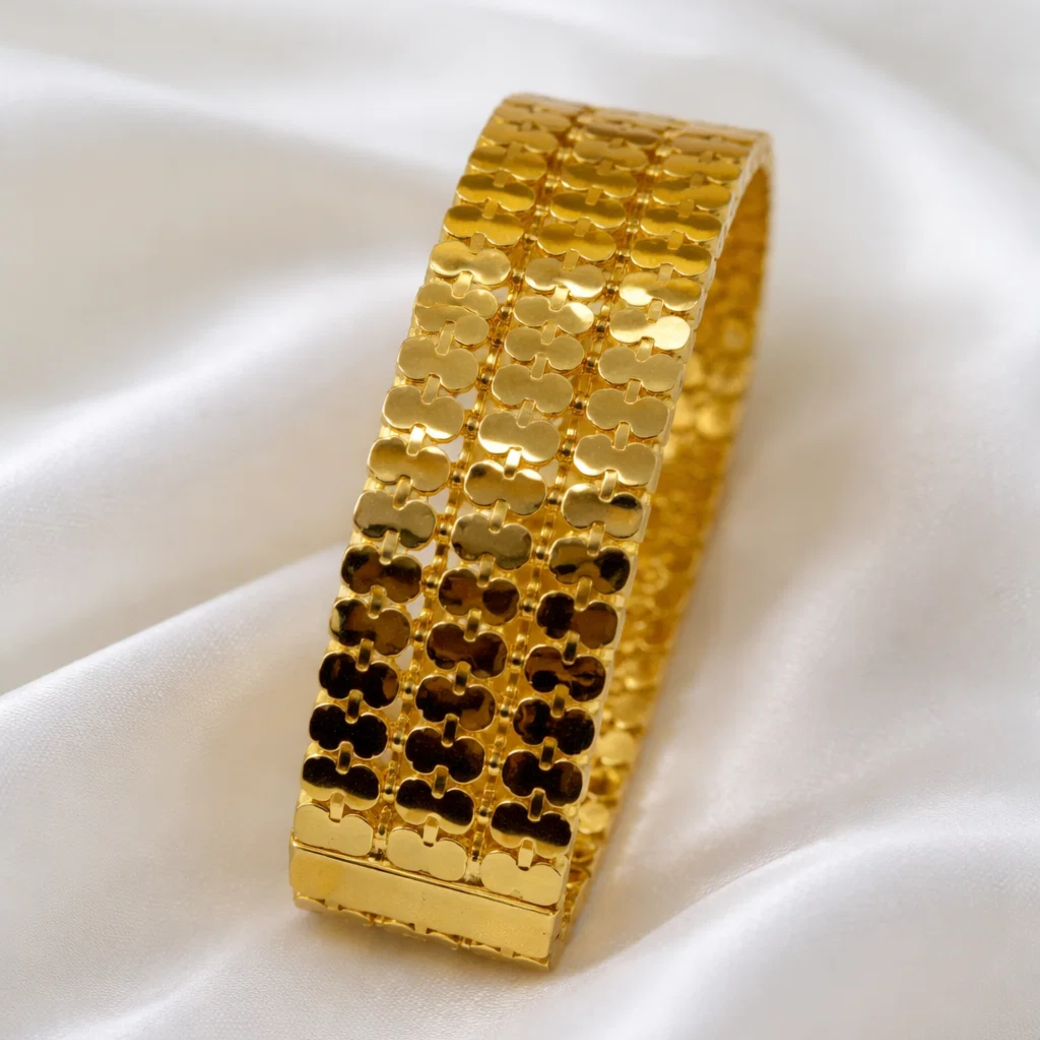 Gold bracelet with a textured pattern on a white background