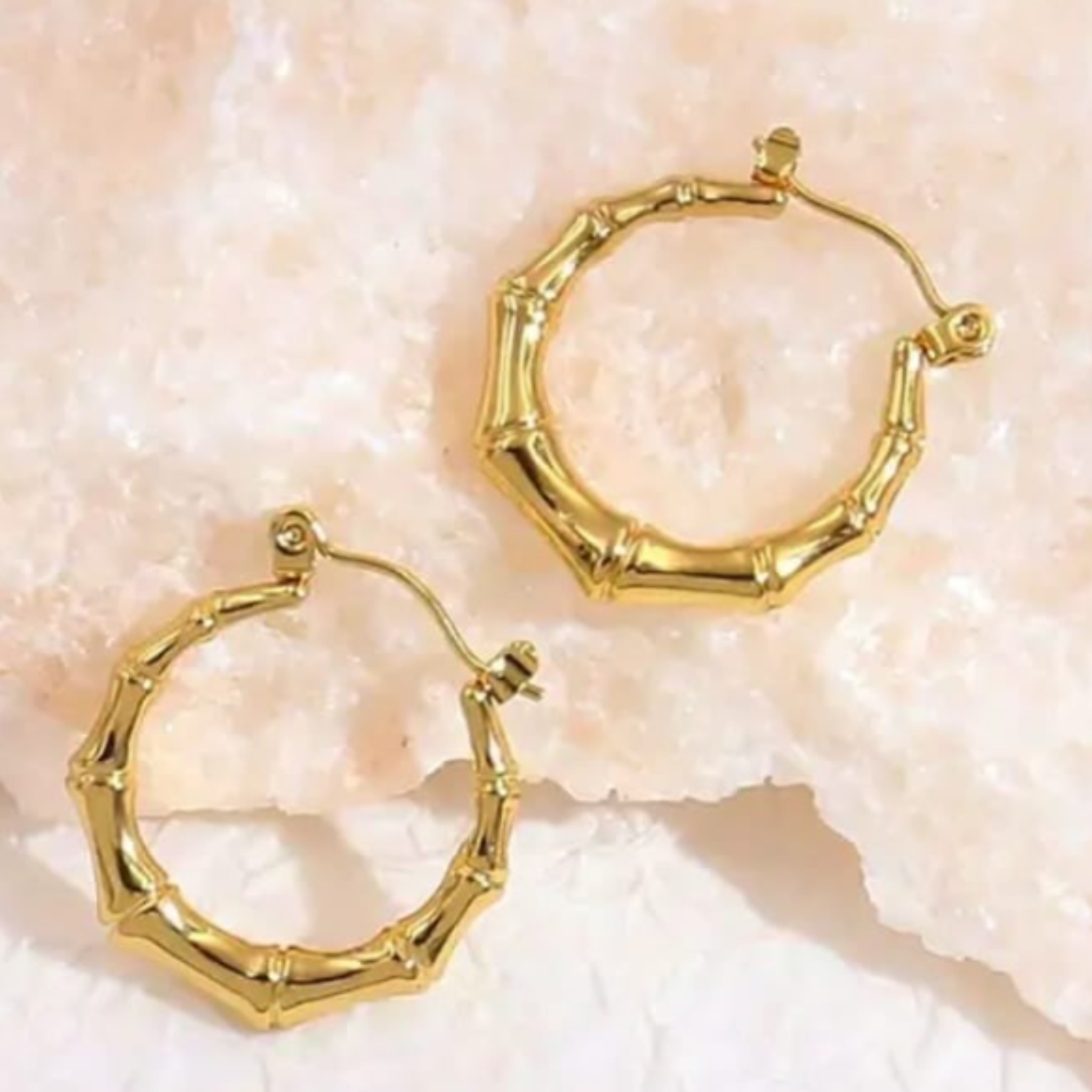 Gold hoop earrings on a textured beige surface