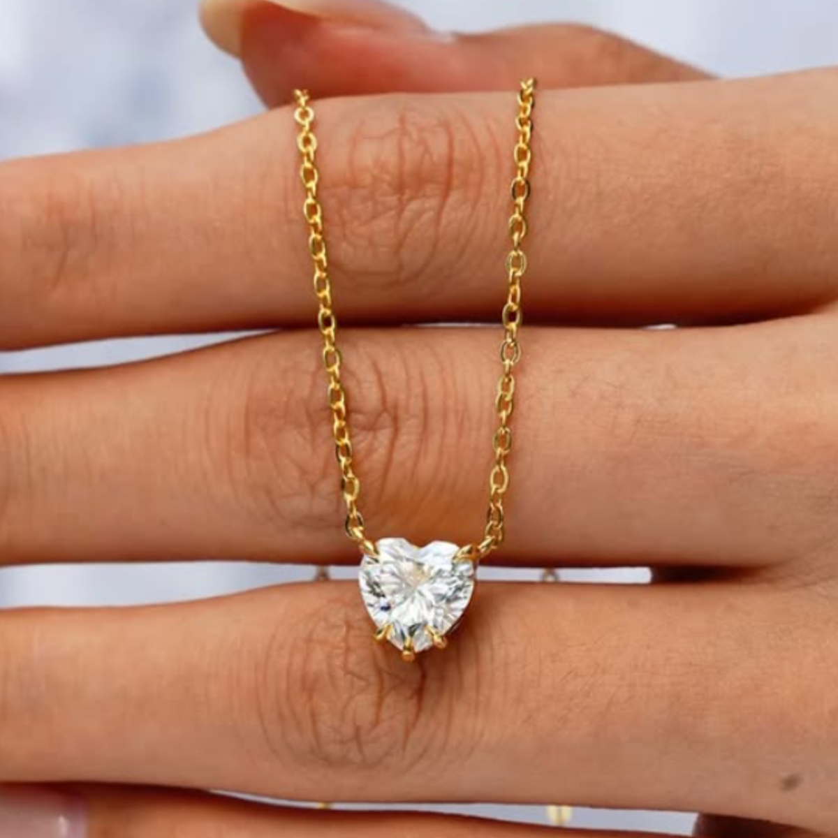 A woman holding a heart pendant with gold chain