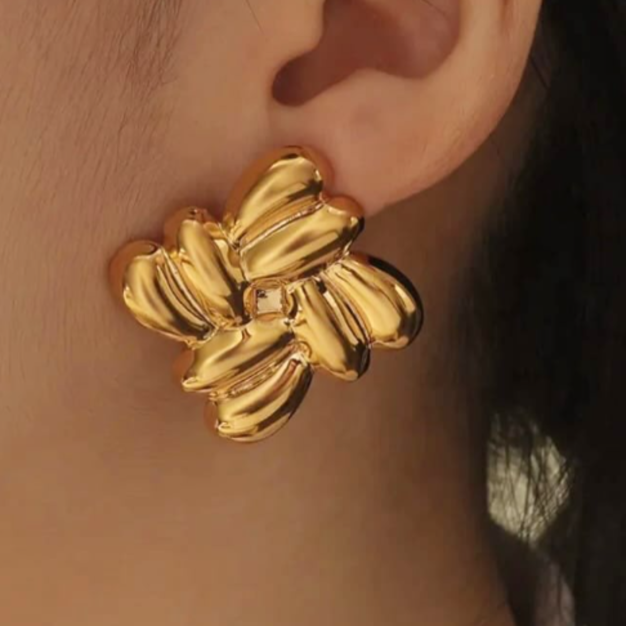 A woman wearing a gold cluster earring