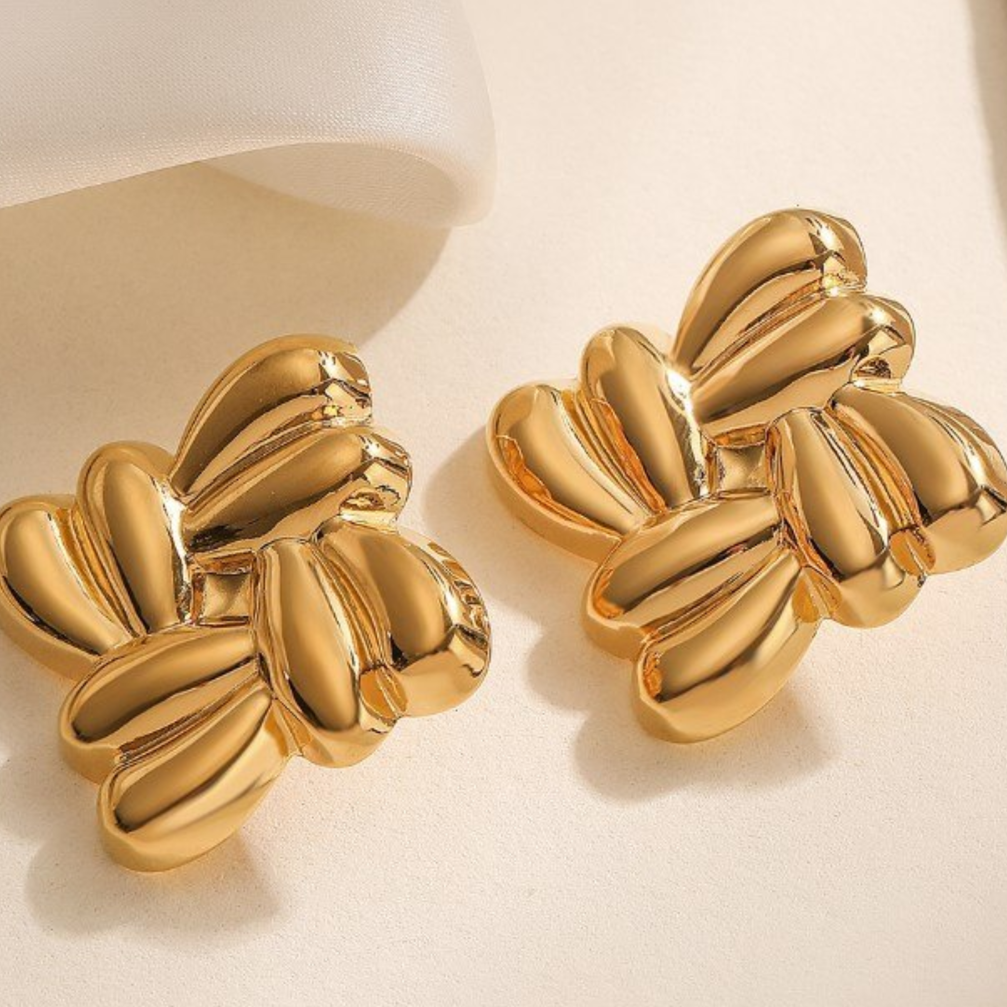 Pair of gold earrings on a beige background