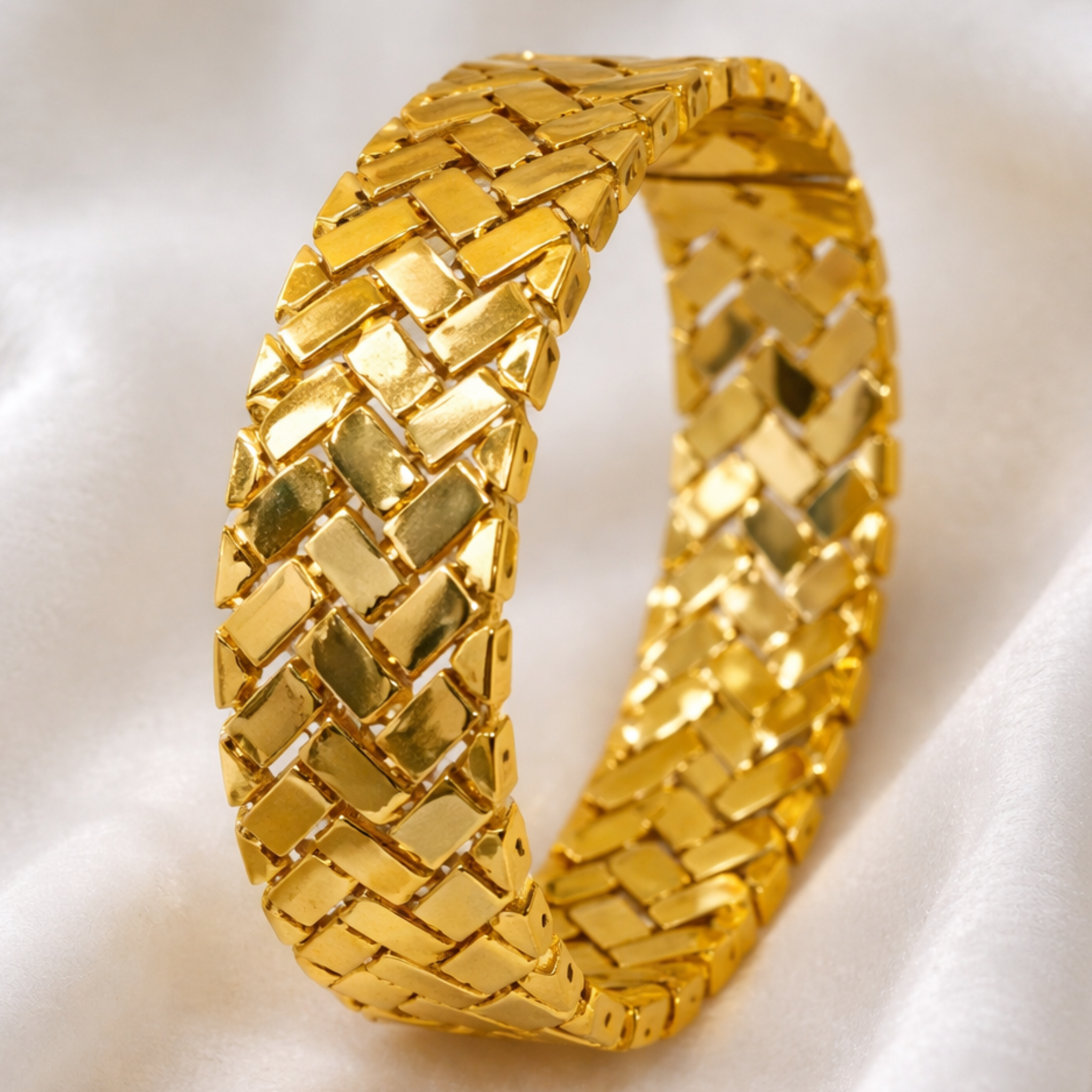 Gold bracelet with a woven pattern on a white background