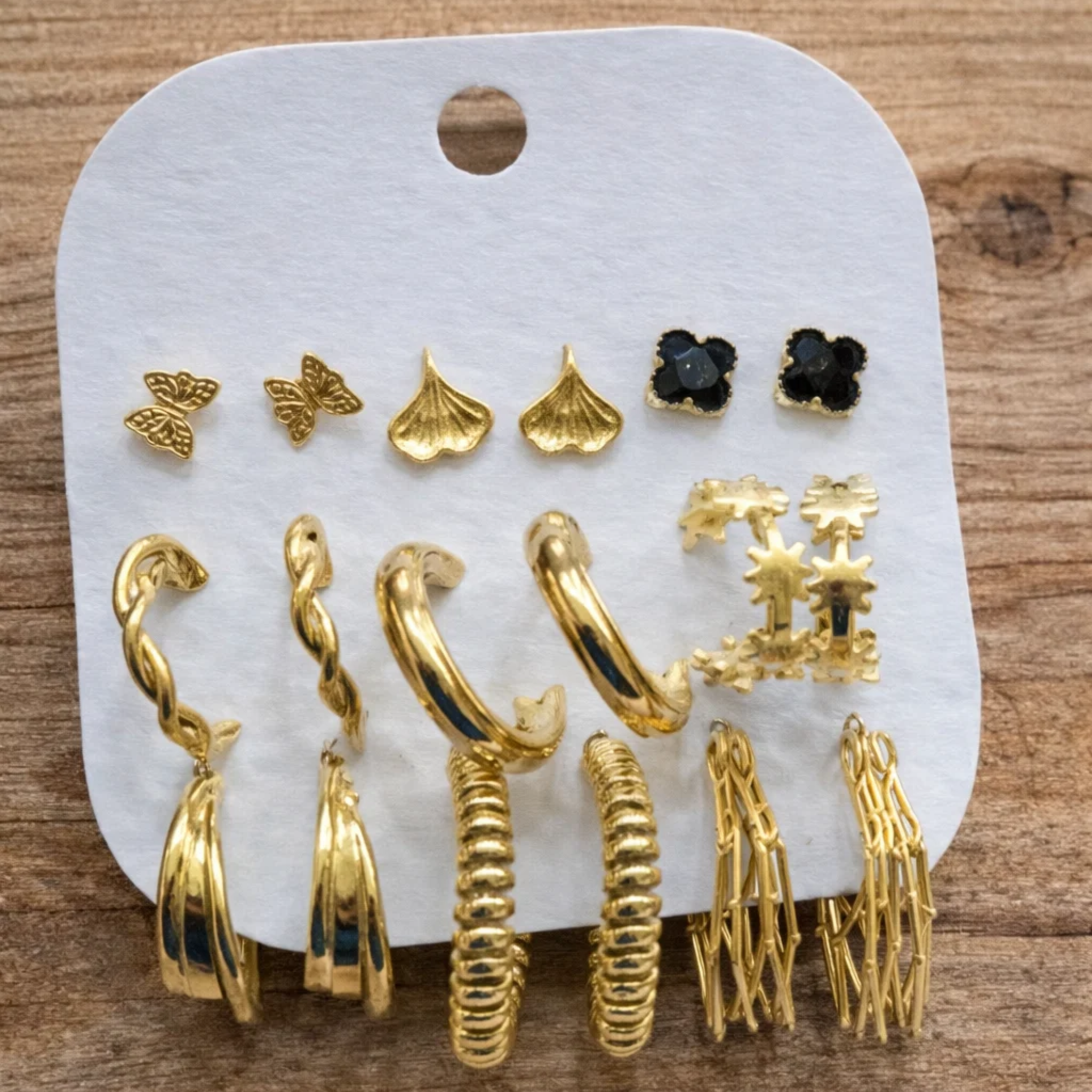 Assorted gold earrings on a white card 