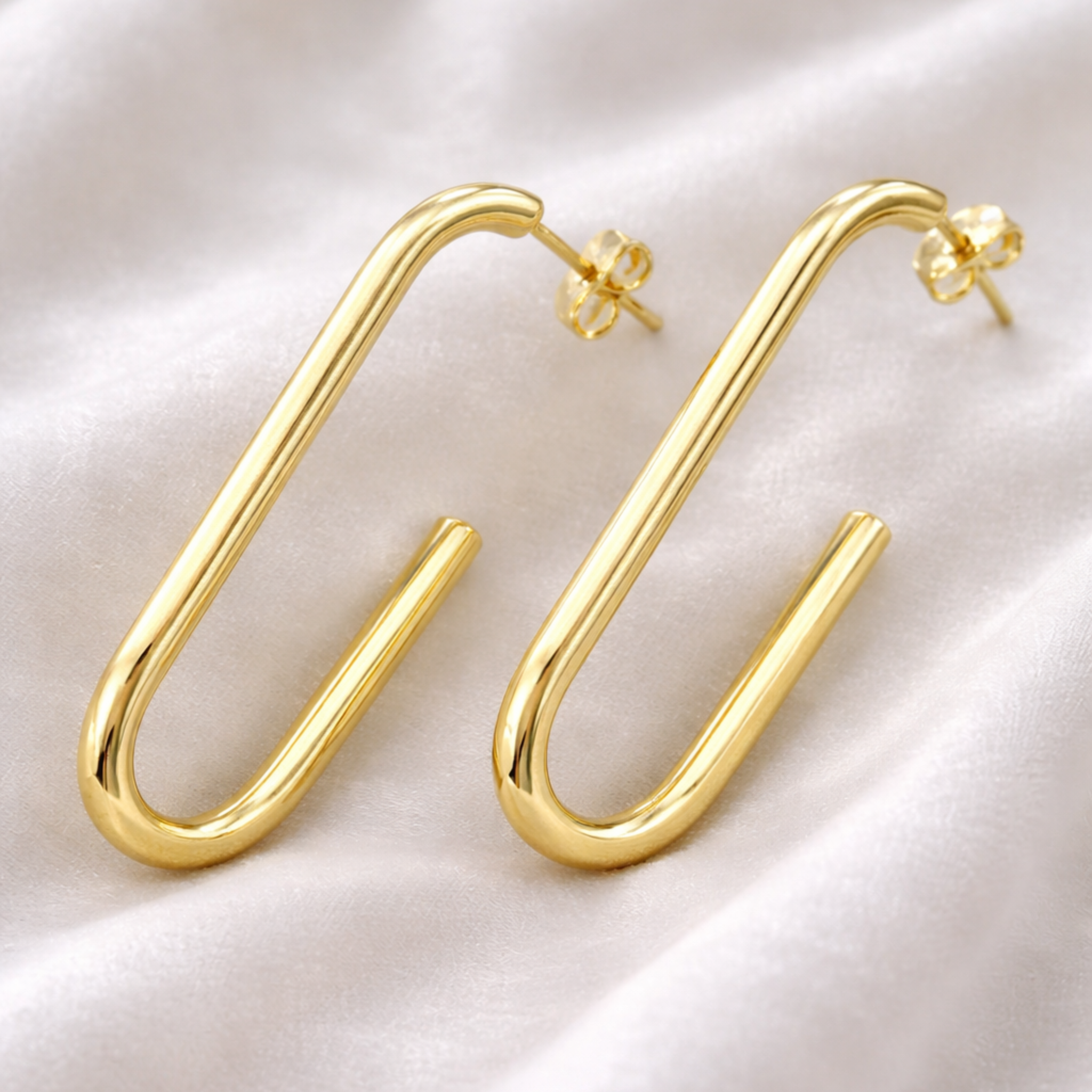 Gold hoop earrings on a light fabric background