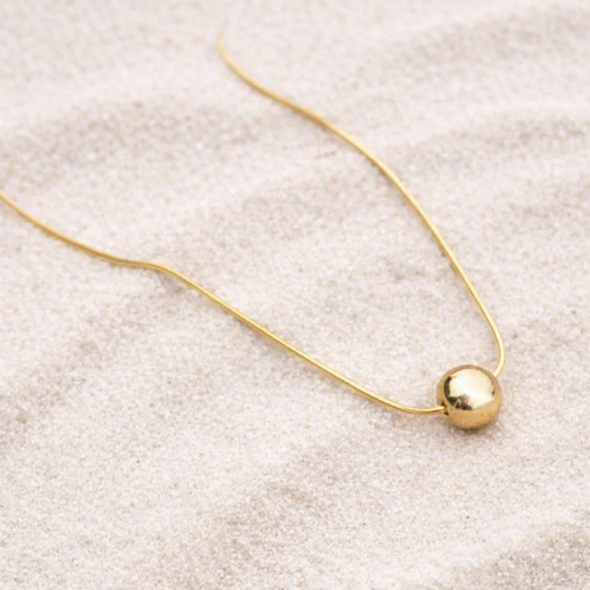 Gold necklace with a single spherical pendant 