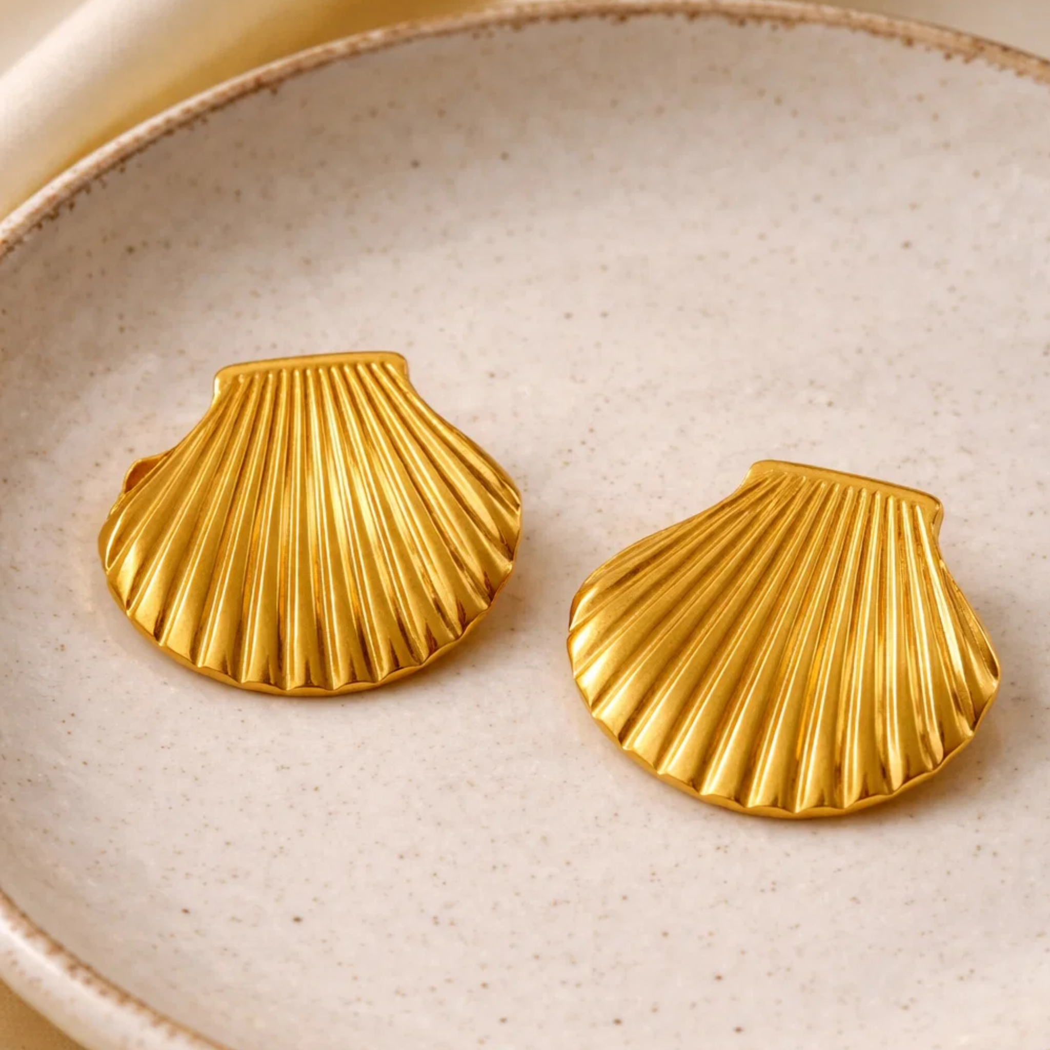 Gold shell earrings on a ceramic plate