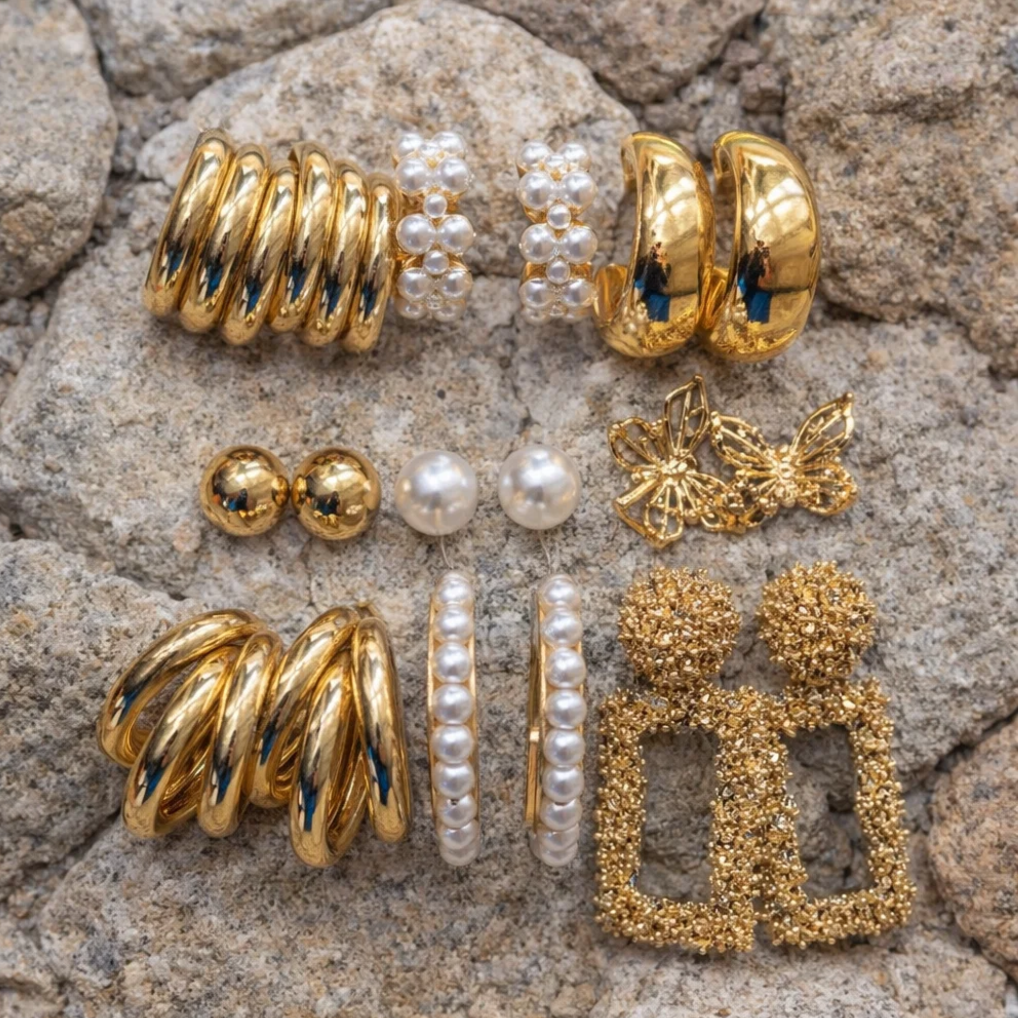 Collection of gold and pearl earrings on a stone surface