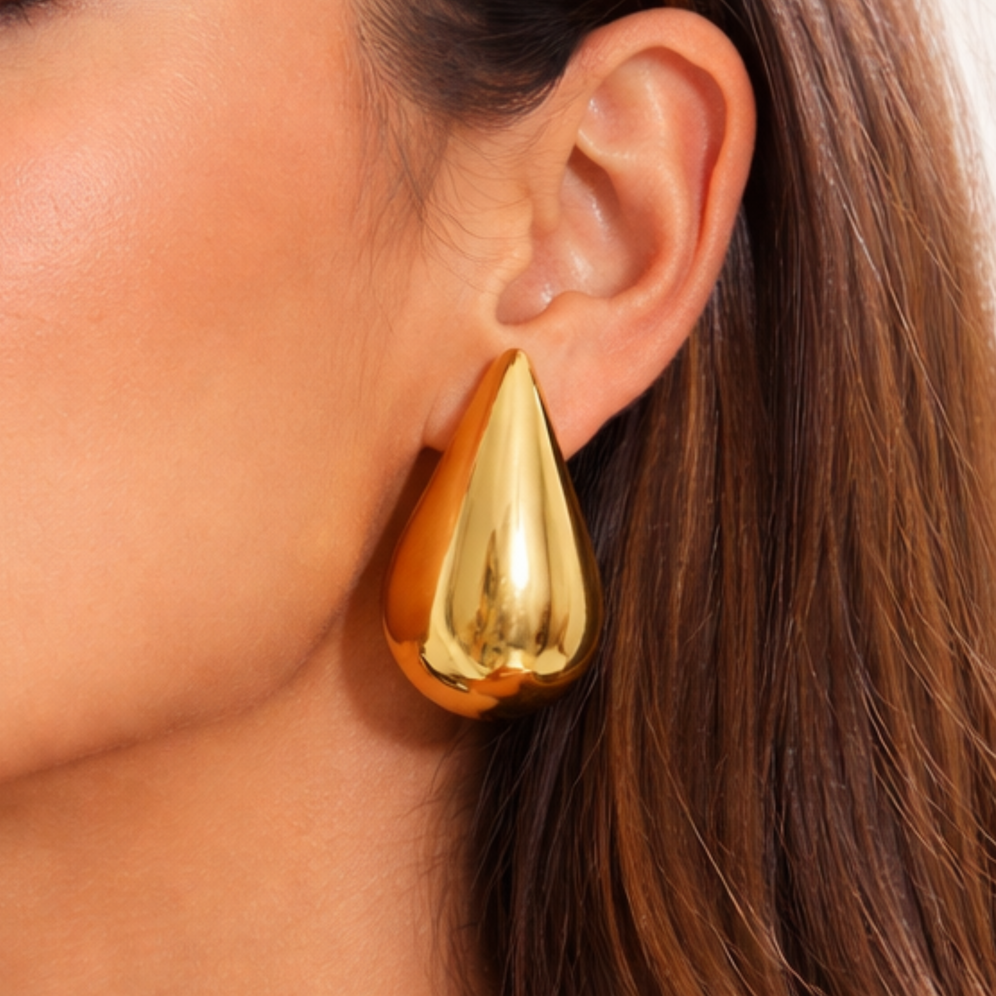 Woman wearing gold teardrop earring