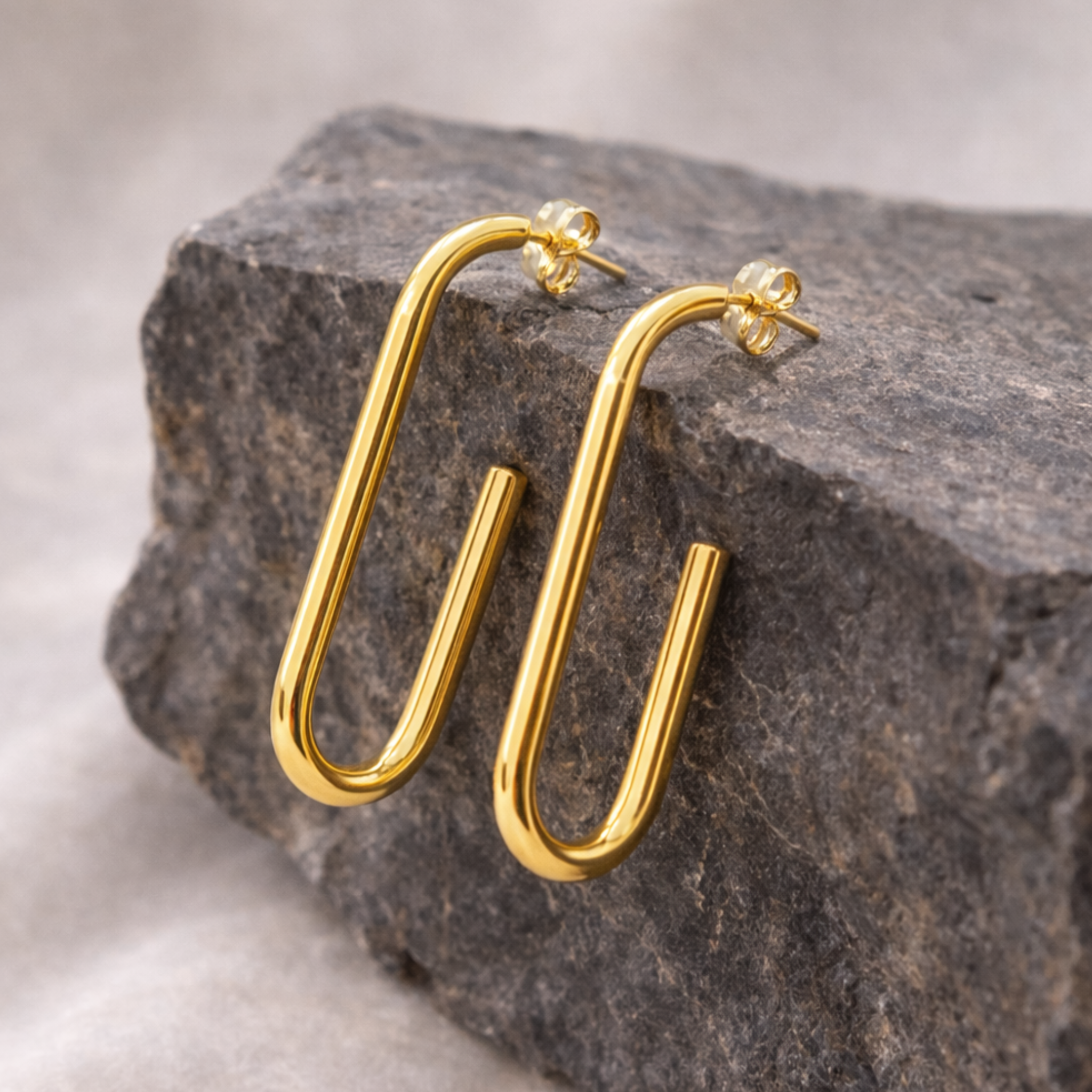 Gold hoop earrings on a stone surface