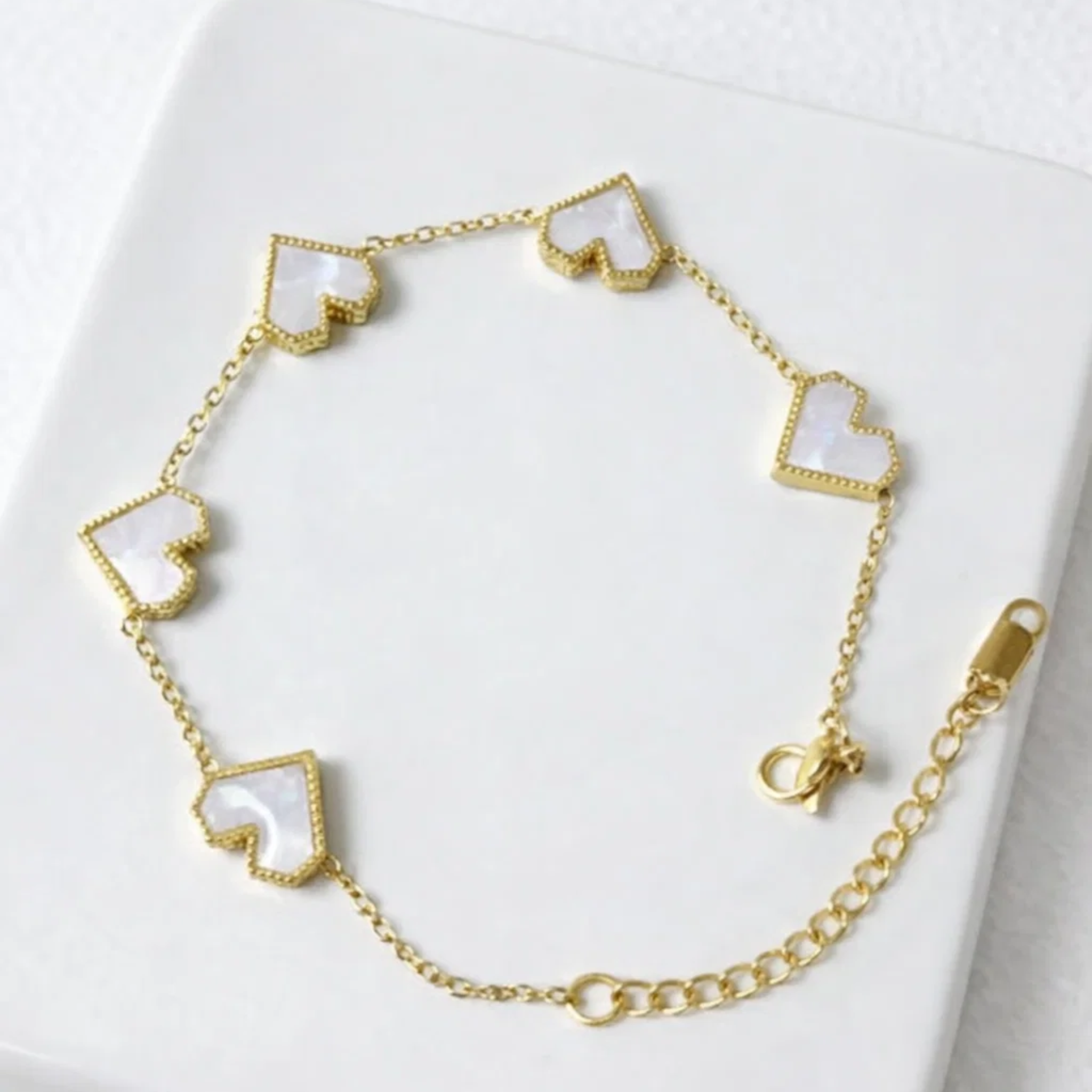 Gold bracelet with heart-shaped charms on a white background
