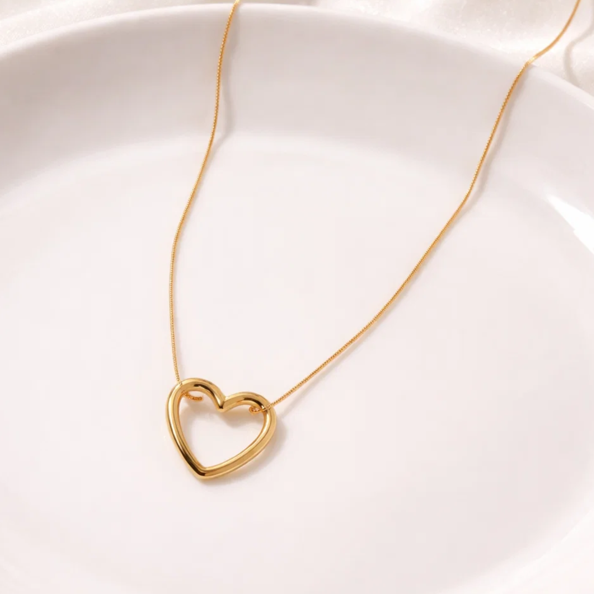 Gold heart-shaped necklace on a white background