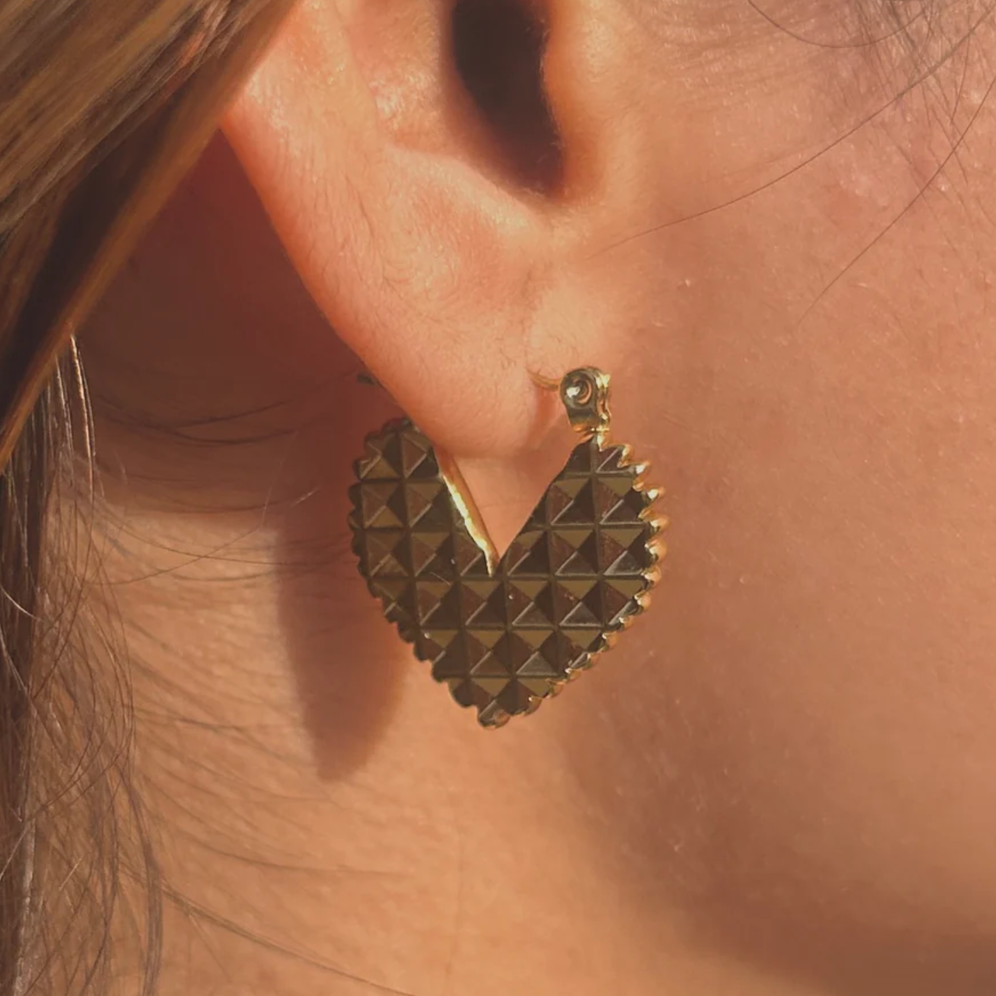 A woman wearing a heart-shaped hoop earrings
