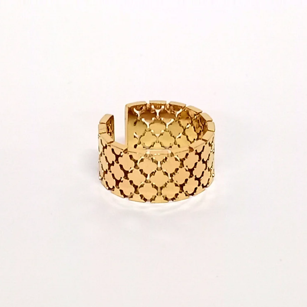 A gold-plated cuff ring on a white surface