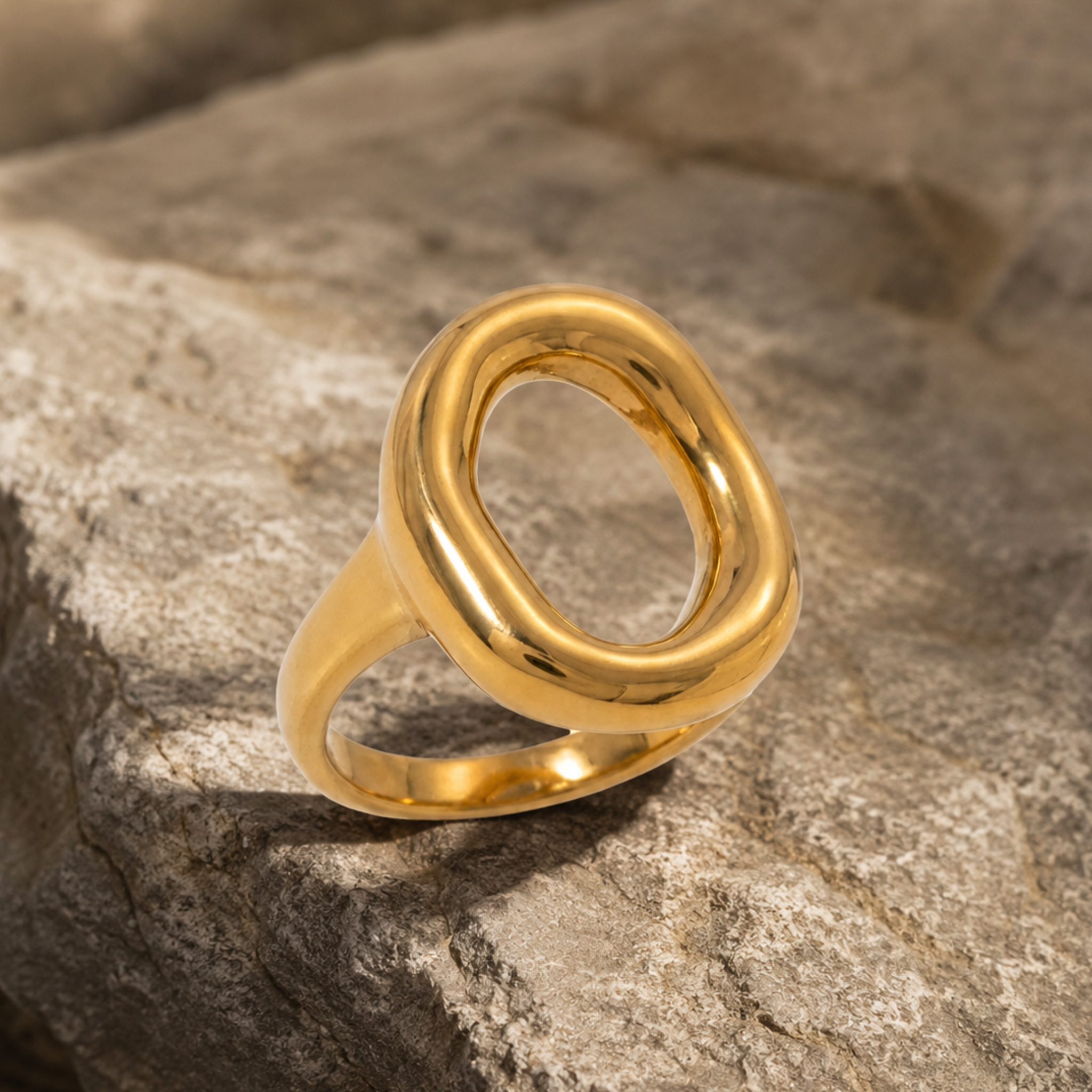 A modern sculptural circle ring on a rock background