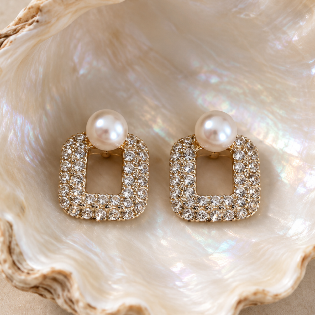 A pair of gold square stud earrings displayed on a clam shell