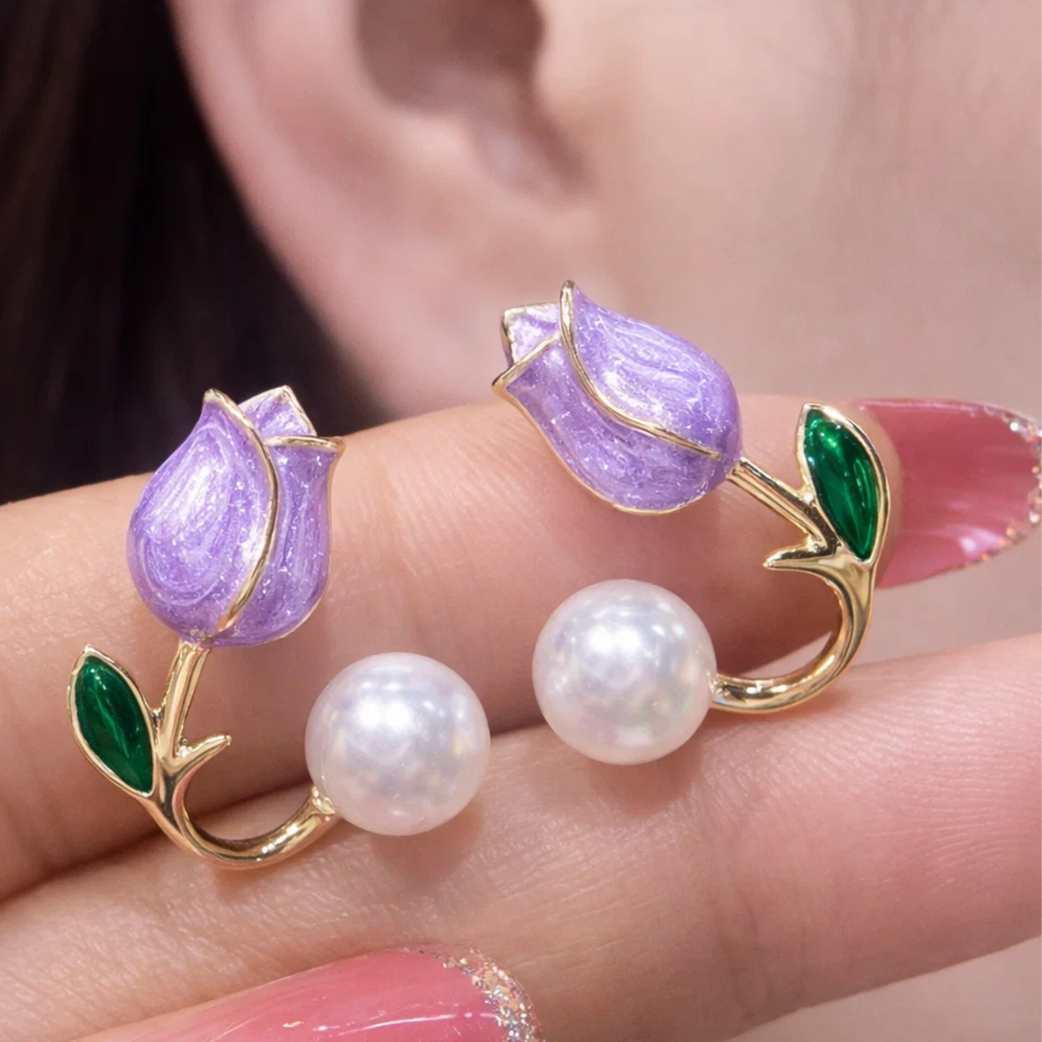 Purple tulip-shaped earrings with pearl centers on a hand