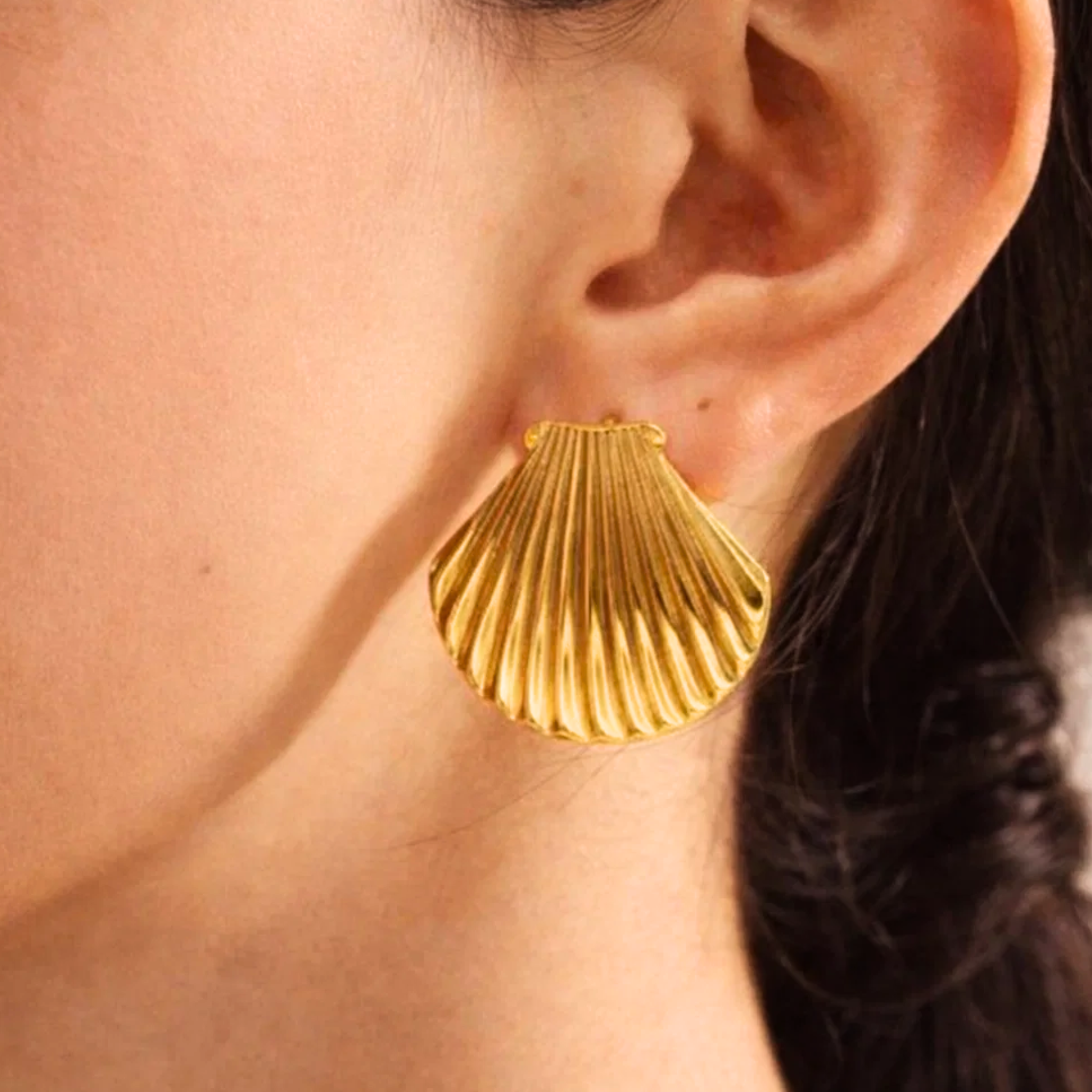 Gold shell-shaped earring worn by a woman