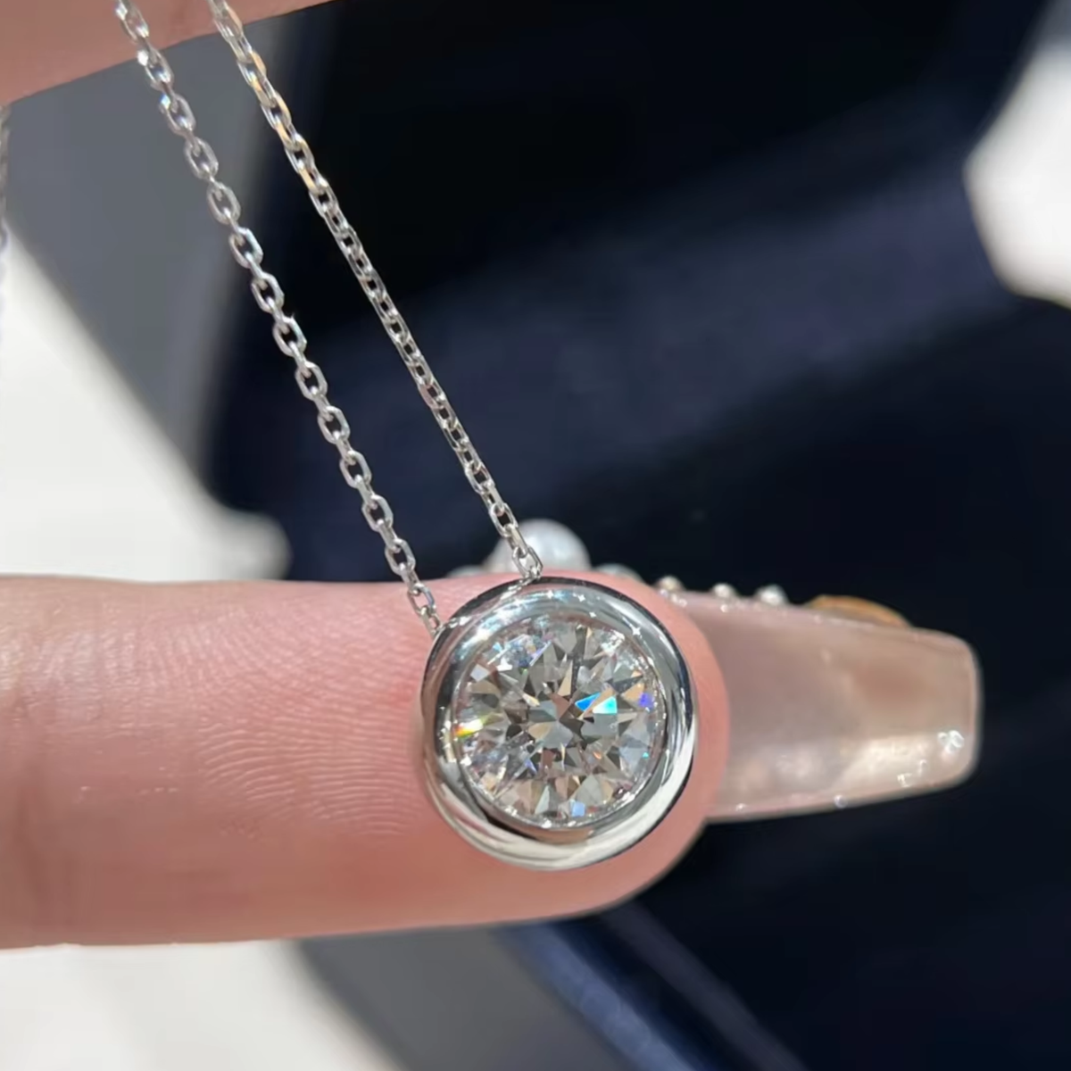 A woman holding a silver sphere pendant necklace