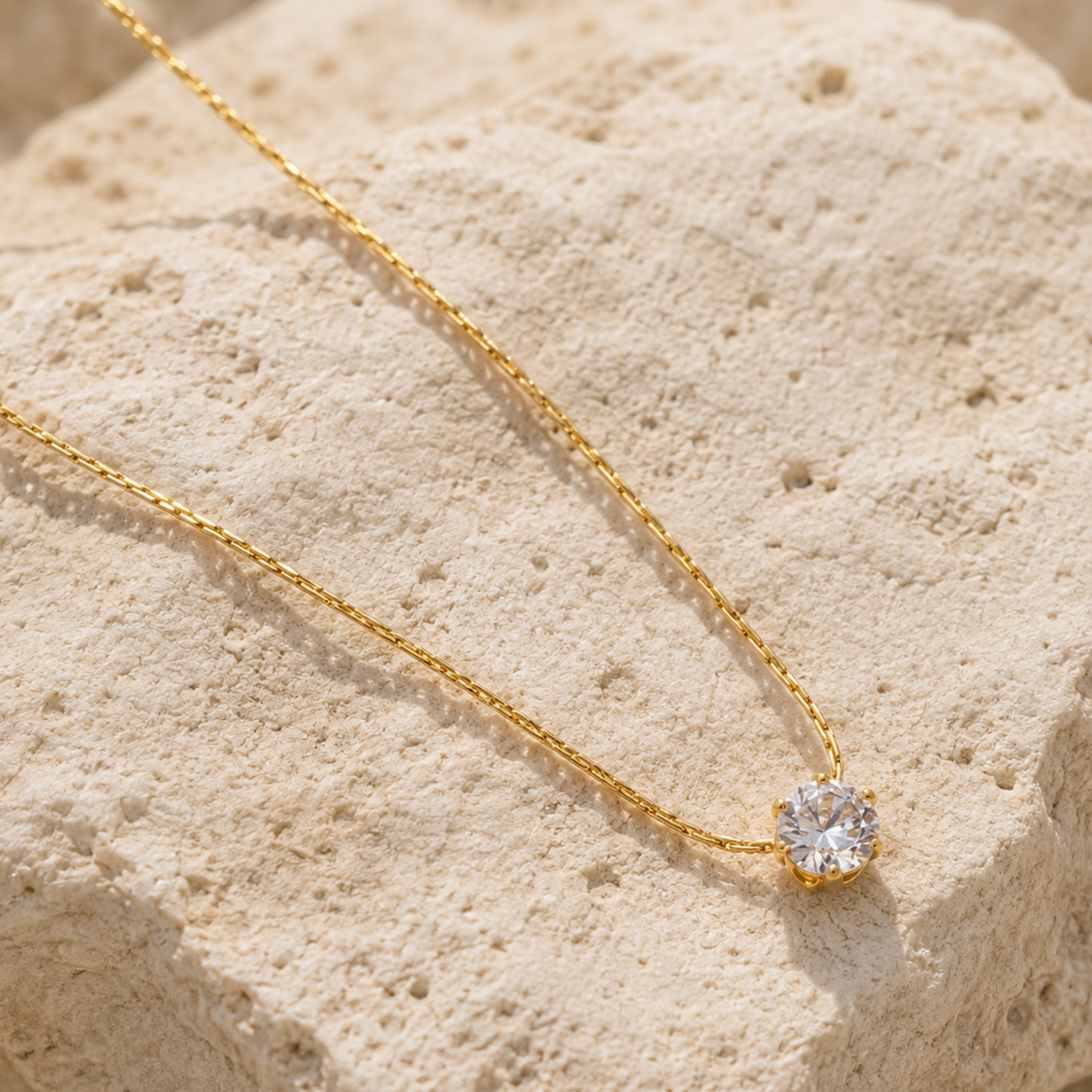 A delicate gold chain necklace on a rock surface