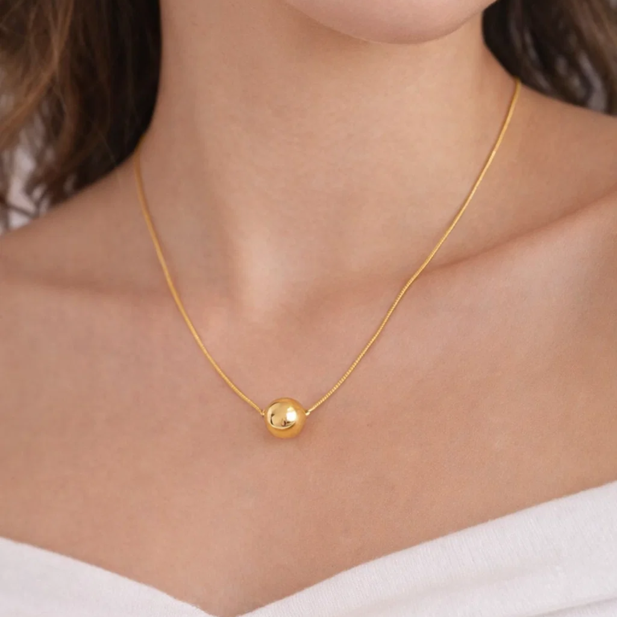 A woman wearing a ball pendant necklace