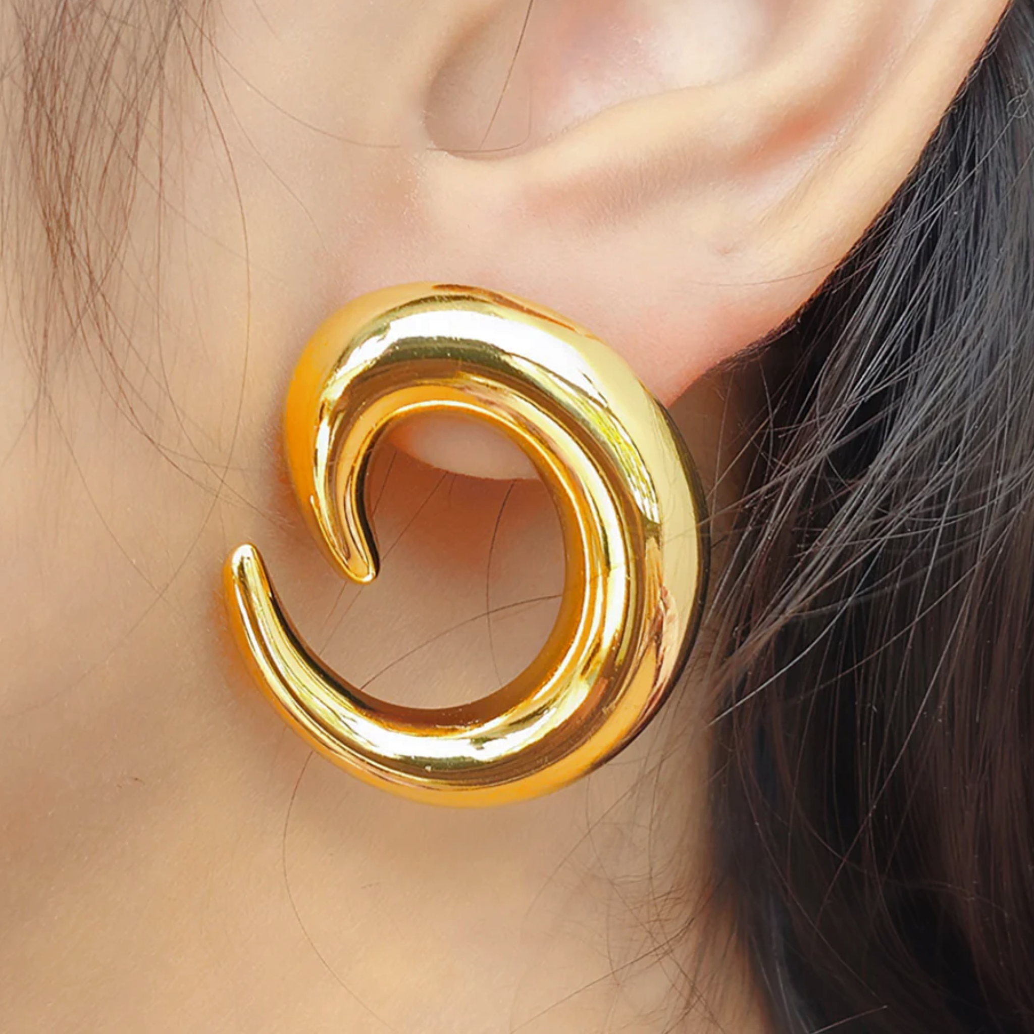 A woman wearing spiral earring of gold color