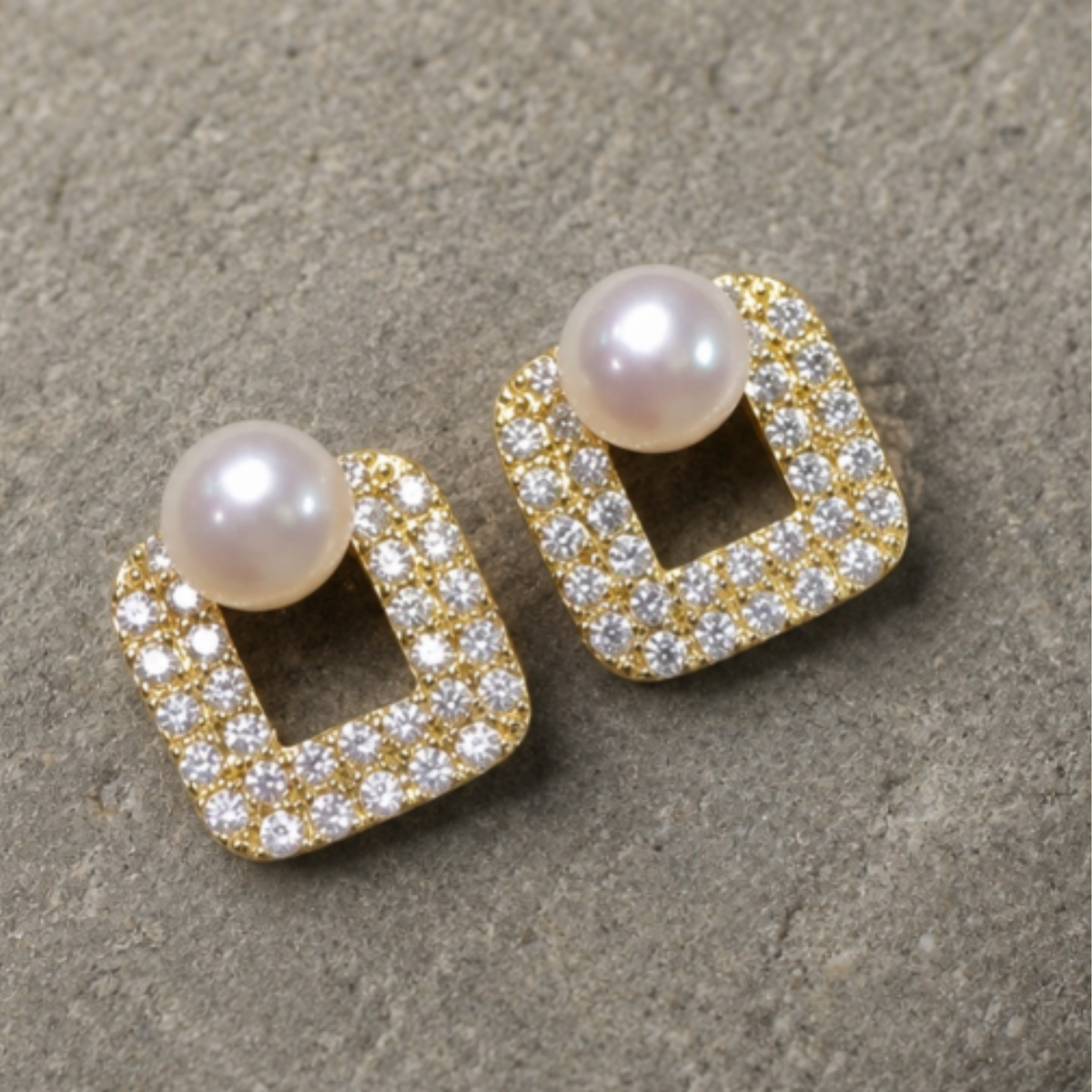 A pair of gold square stud earrings with a central open square design,