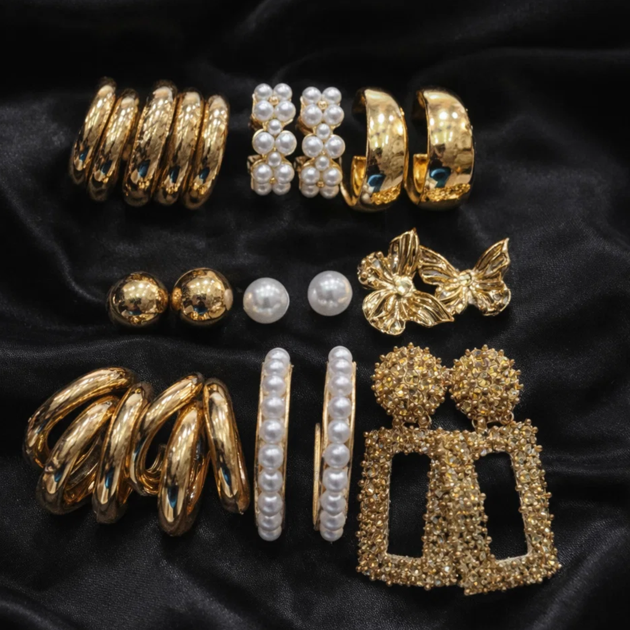 Collection of gold and pearl earrings on a black background