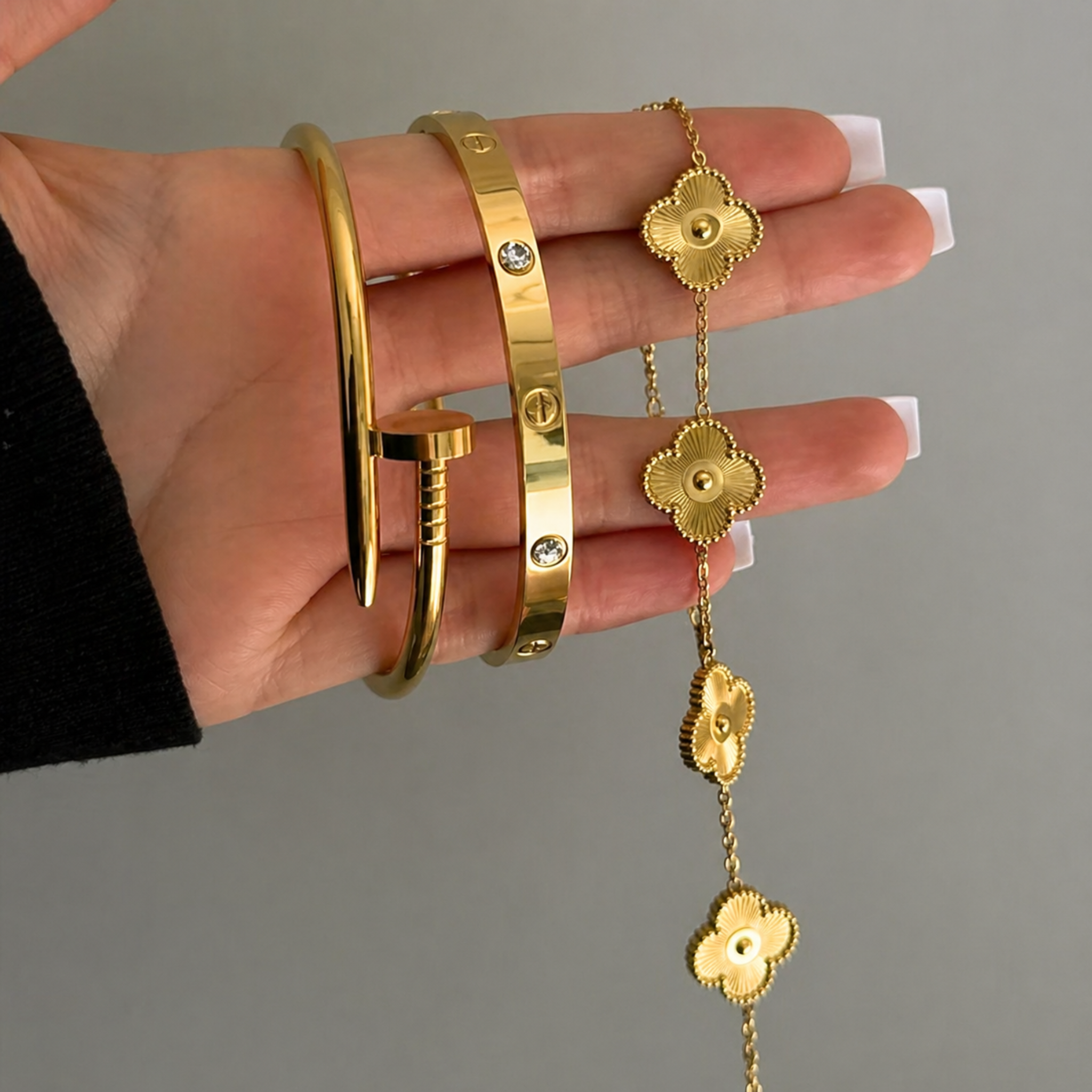 A woman holding a nail bangle, Cartier bangle and a clover bracelet