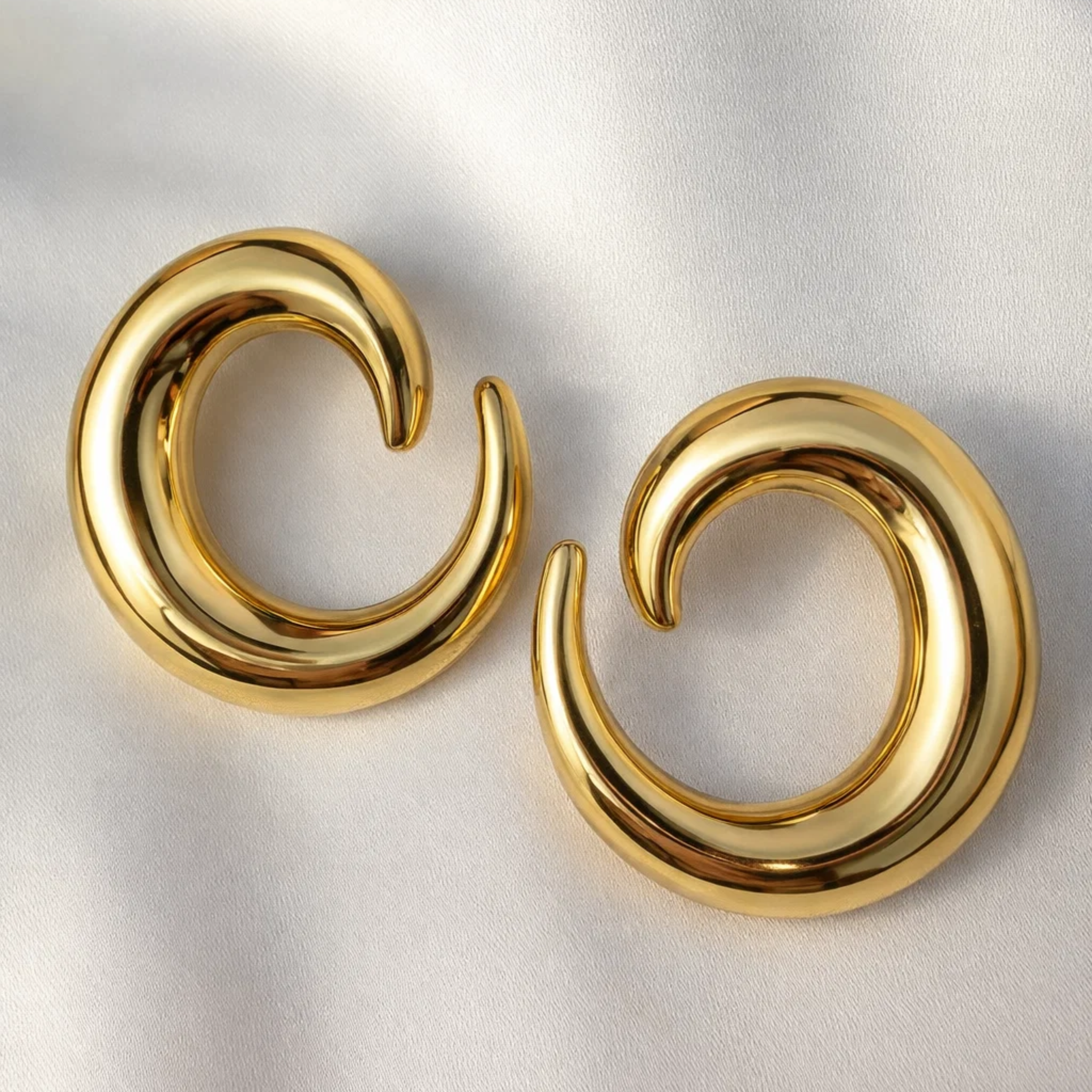 Pair of gold spiral earrings on a light gray background