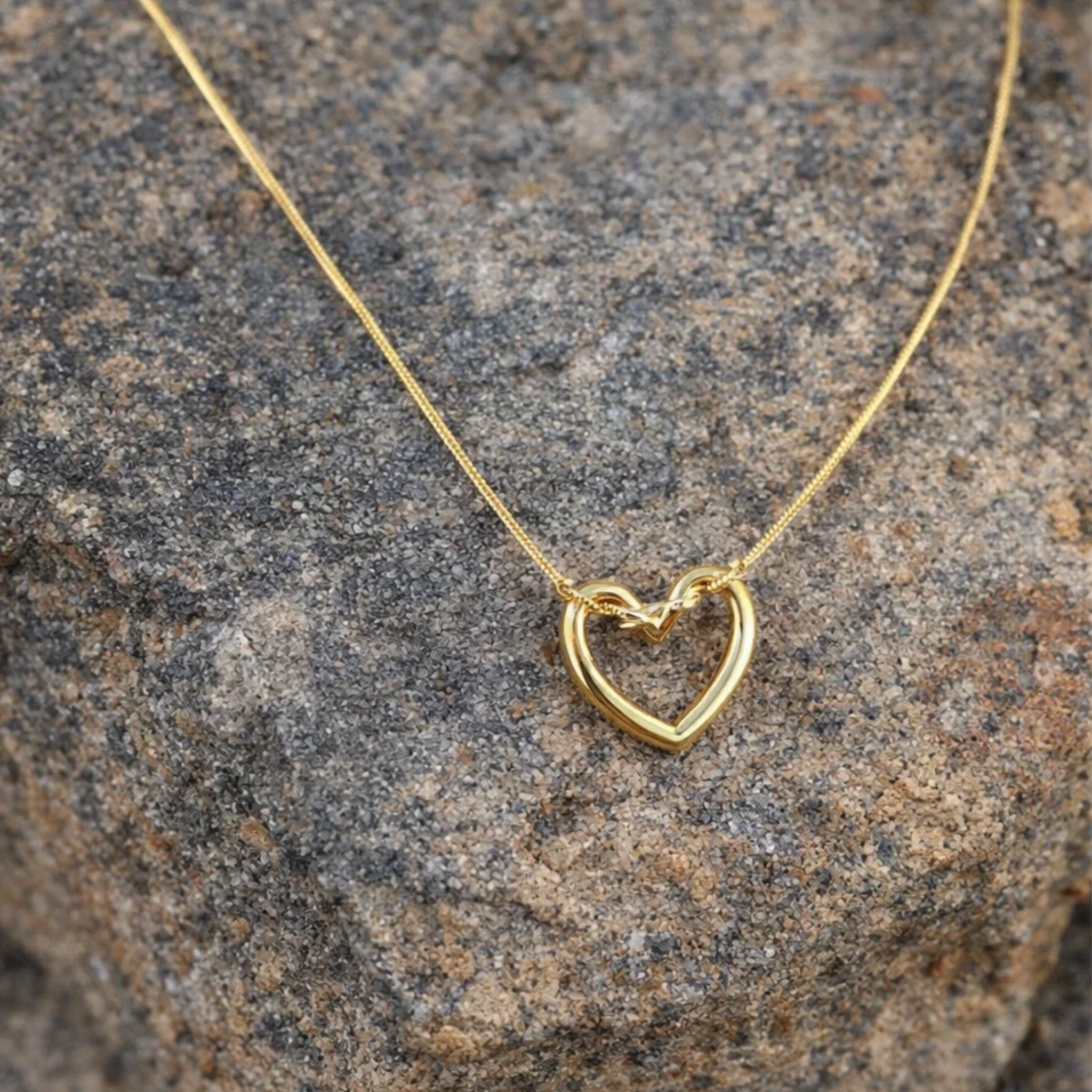 Gold heart-shaped necklace on a stone surface