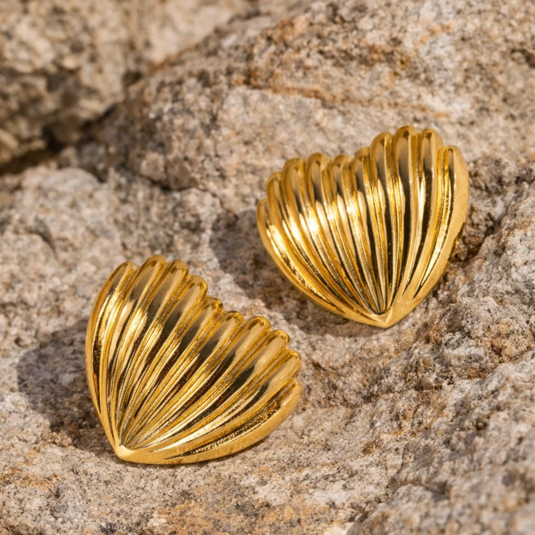 Gold shell-shaped earrings on a textured stone 